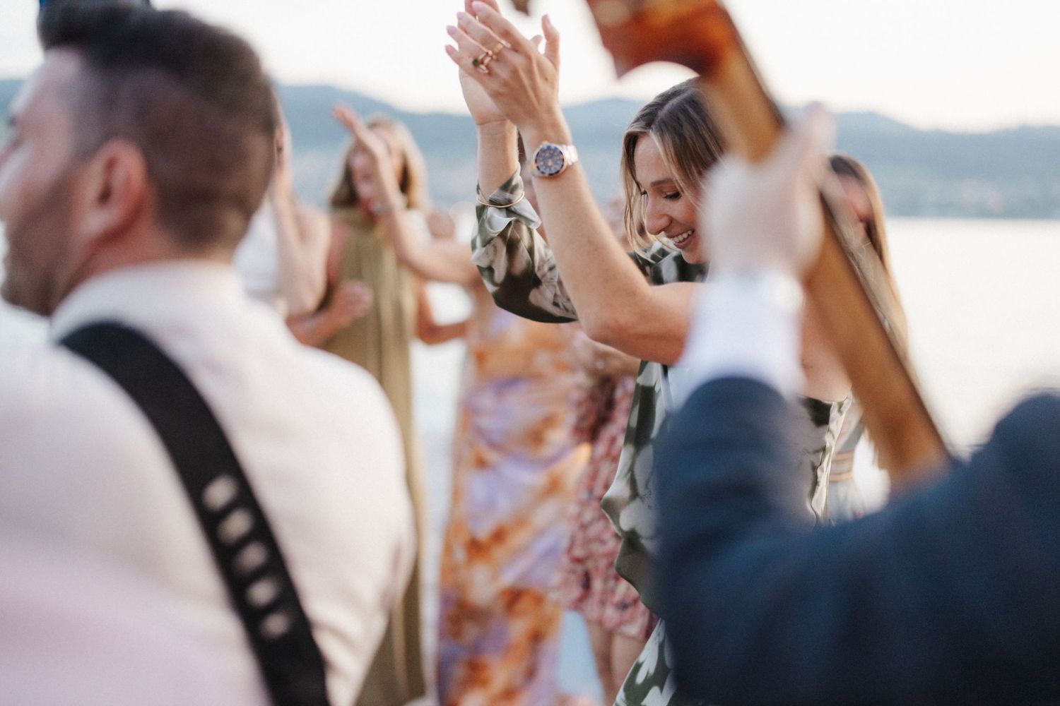 Guests dancing and celebrating outdoors at a wedding reception near the water.
