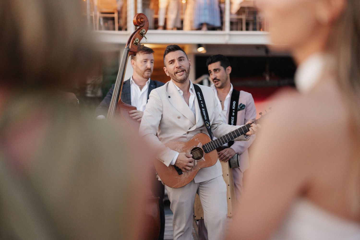 Live band performs at a wedding with guitarist singing and double bass player on a waterfront venue.