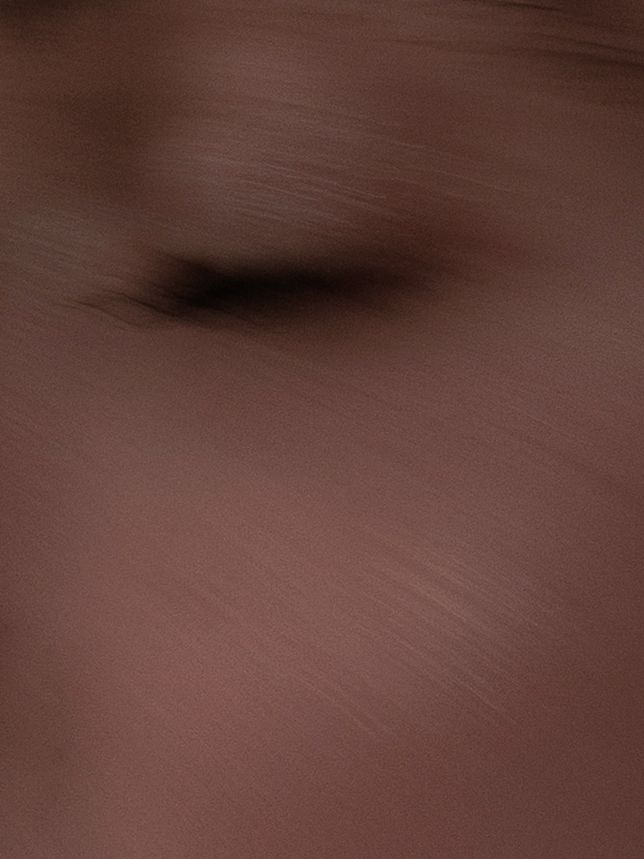 Extreme close-up of smooth brown fabric texture with subtle shadow detail.