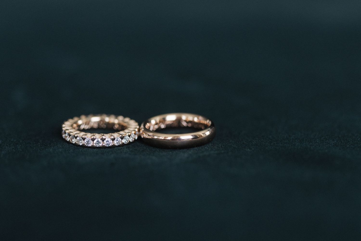 Two rose gold diamond eternity wedding bands on dark background.