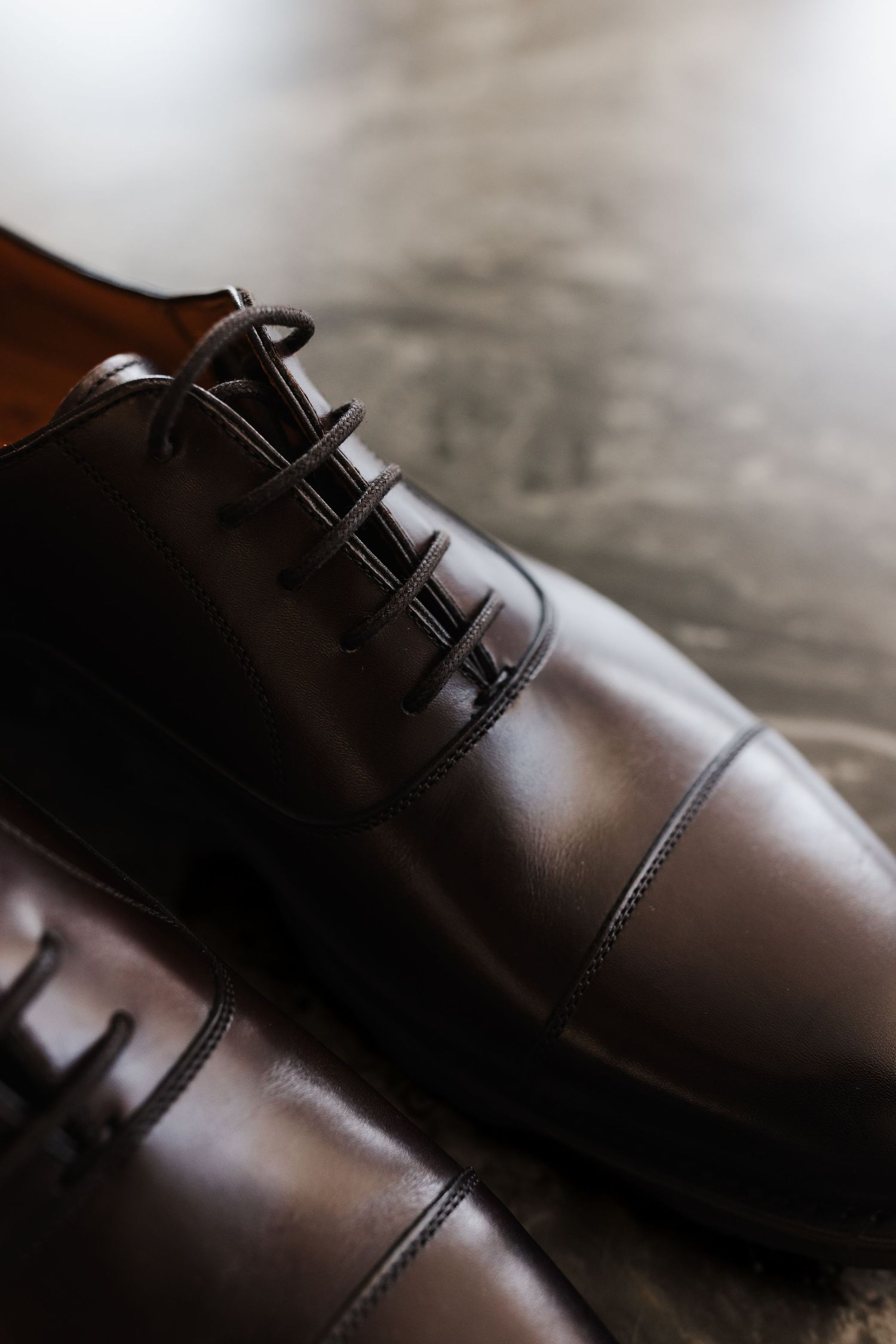 Close-up of polished dark brown leather Oxford cap-toe dress shoes with dark laces.