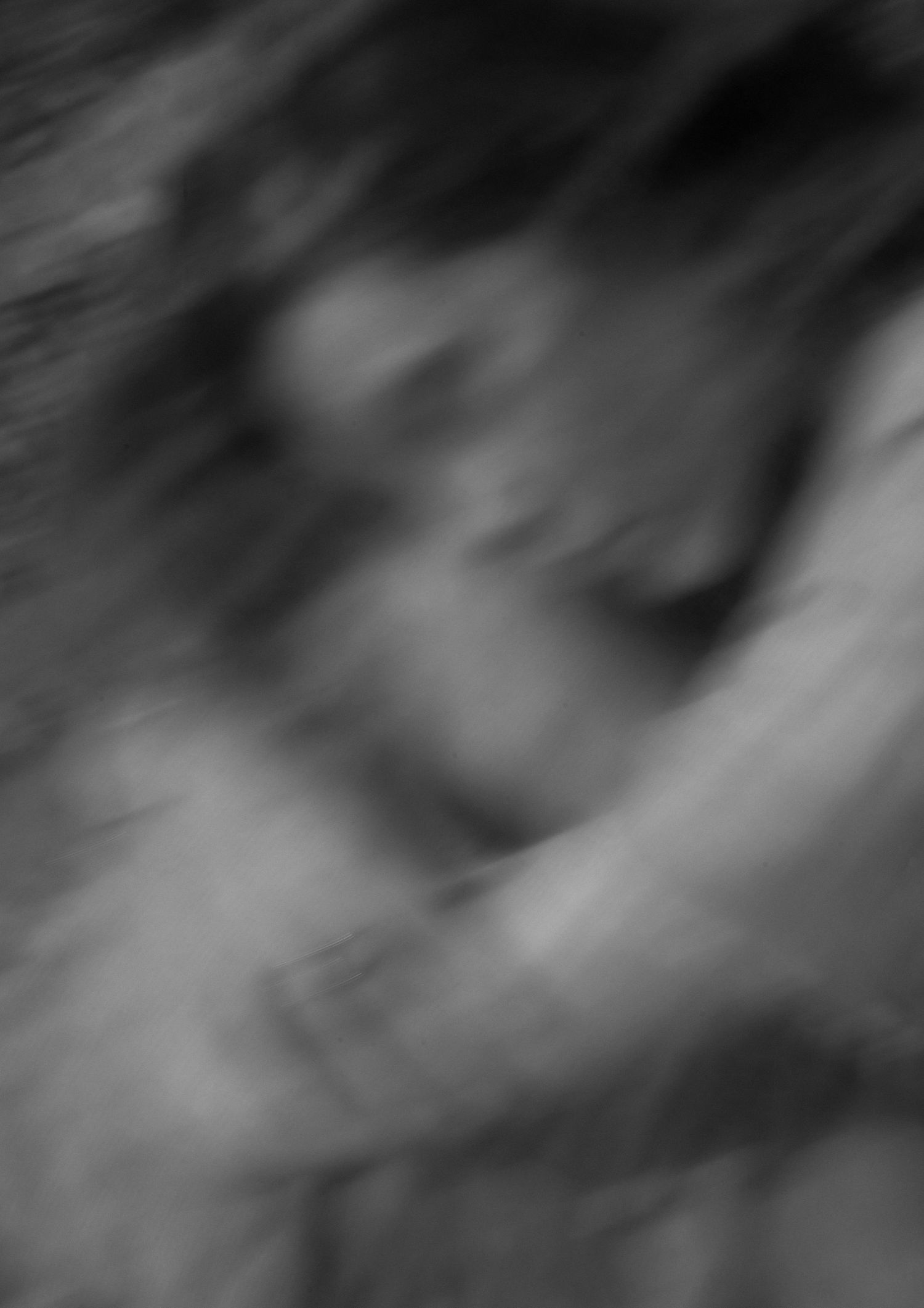 Abstract black and white blurred photograph of intertwined human forms in motion.