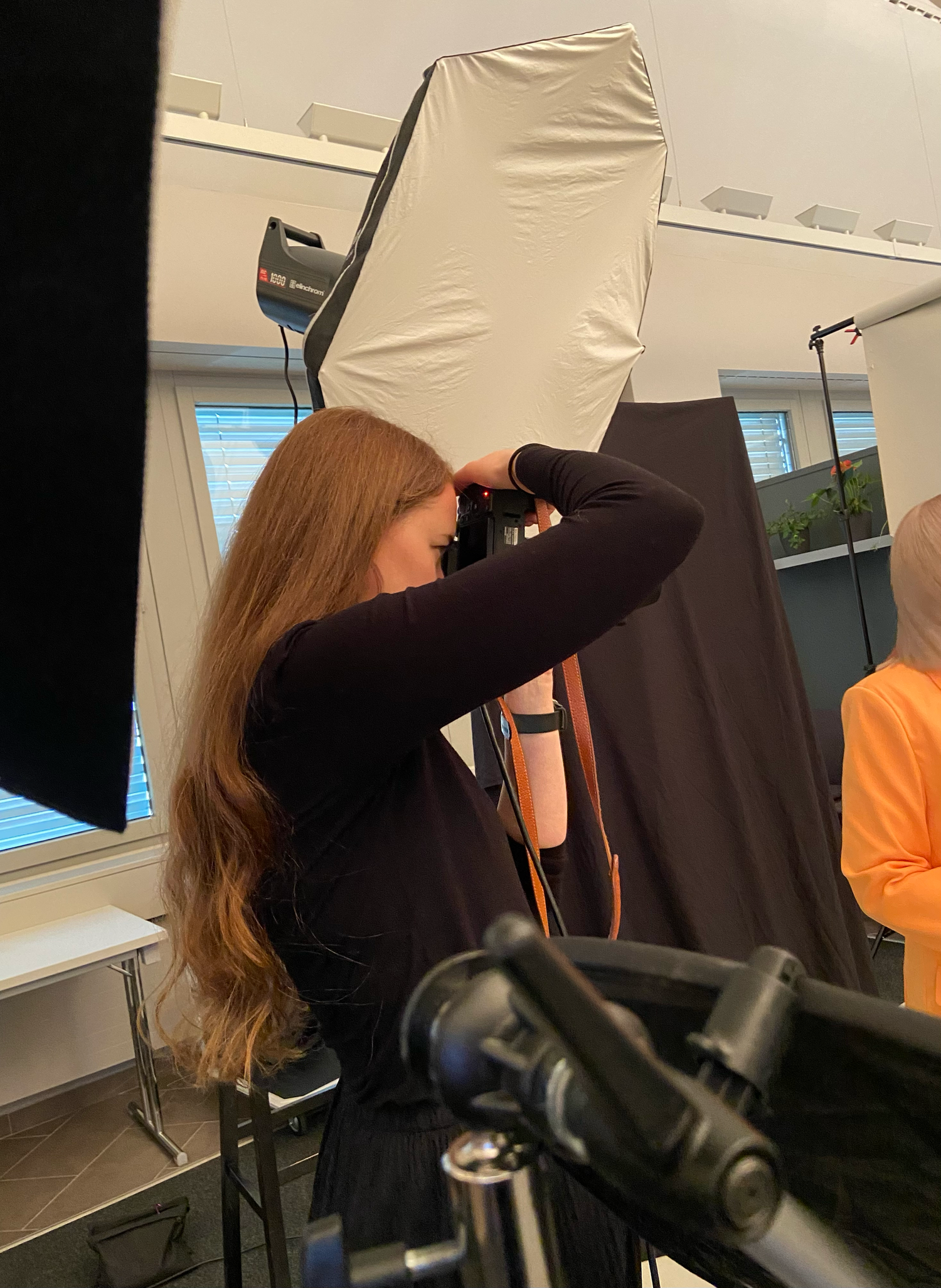 Female photographer with long hair shooting product photography in a professional studio setup.