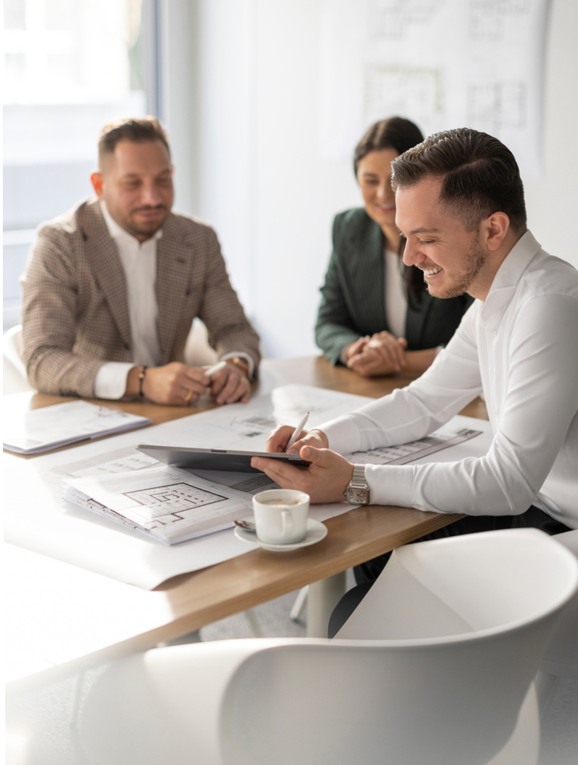 Business professionals in bright office meeting, man in white shirt reviewing documents with tablet.