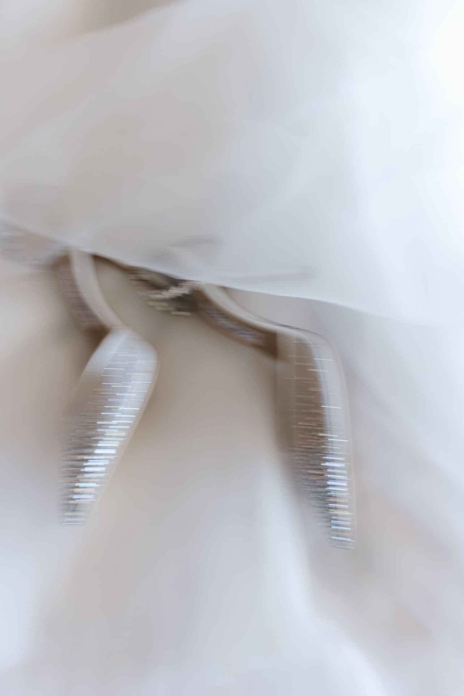 Close-up of delicate white wedding dress fabric with silver ribbon ties and soft tulle layers.