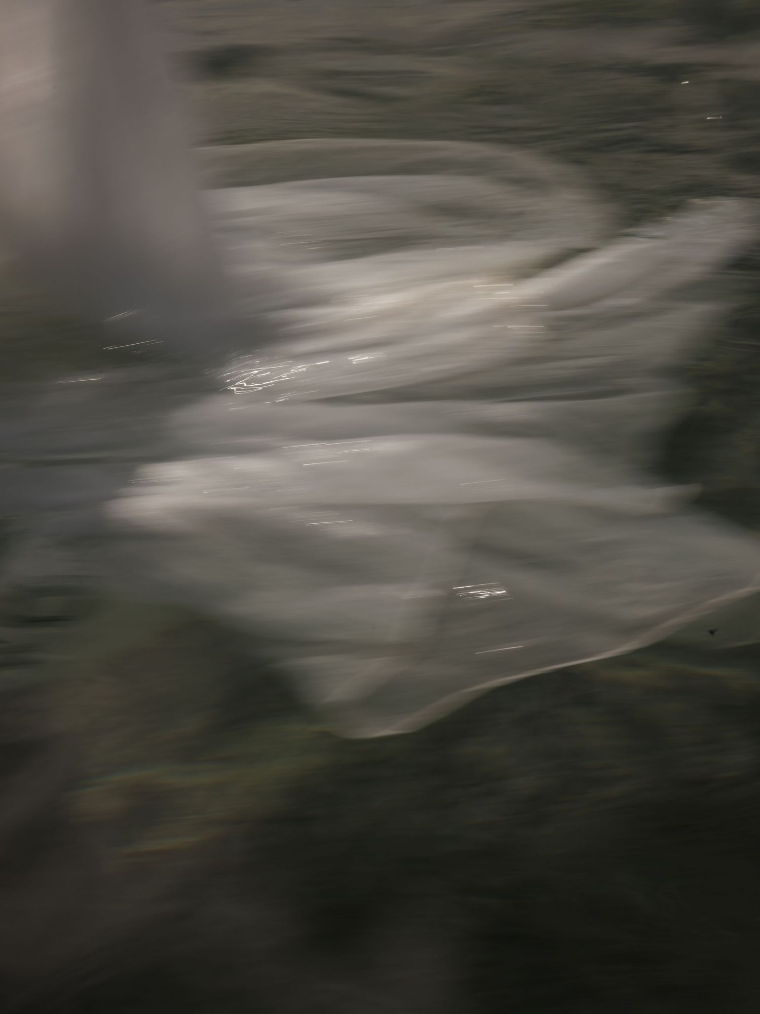 Abstract blurred motion photograph of white fabric flowing over dark water surface.