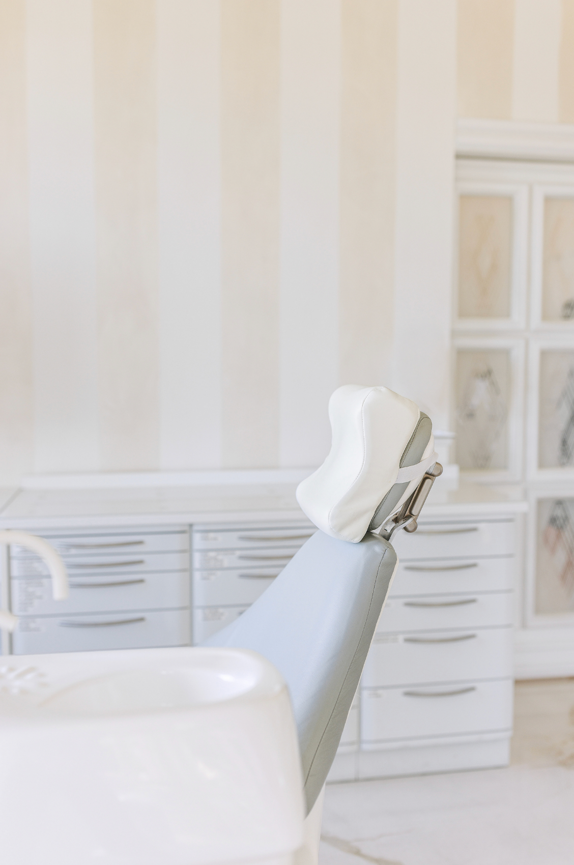 Close-up of a dental chair headrest in a bright, modern dental office interior.