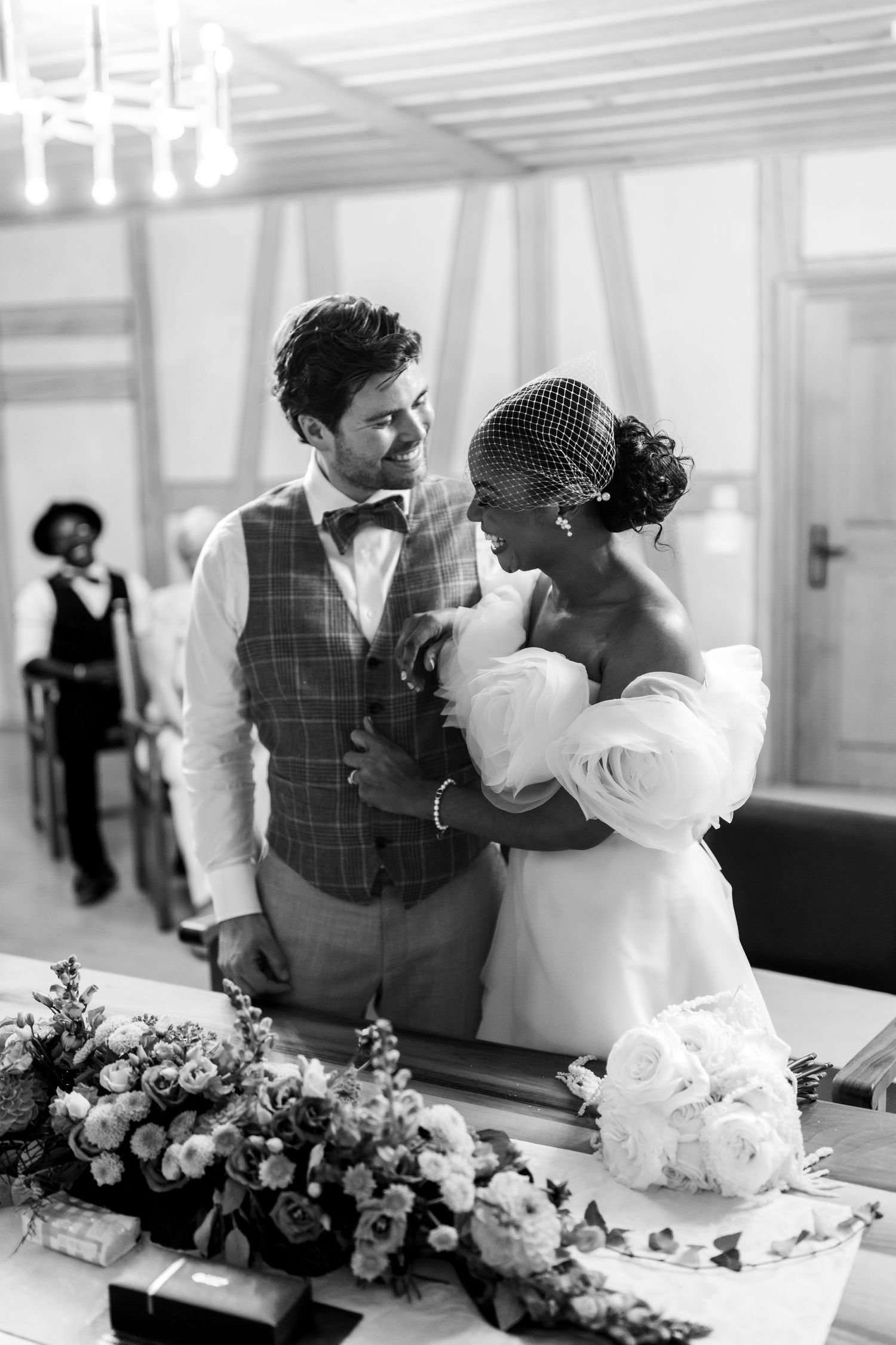 Black and white photo of interracial newlyweds embracing at the altar during their wedding ceremony.