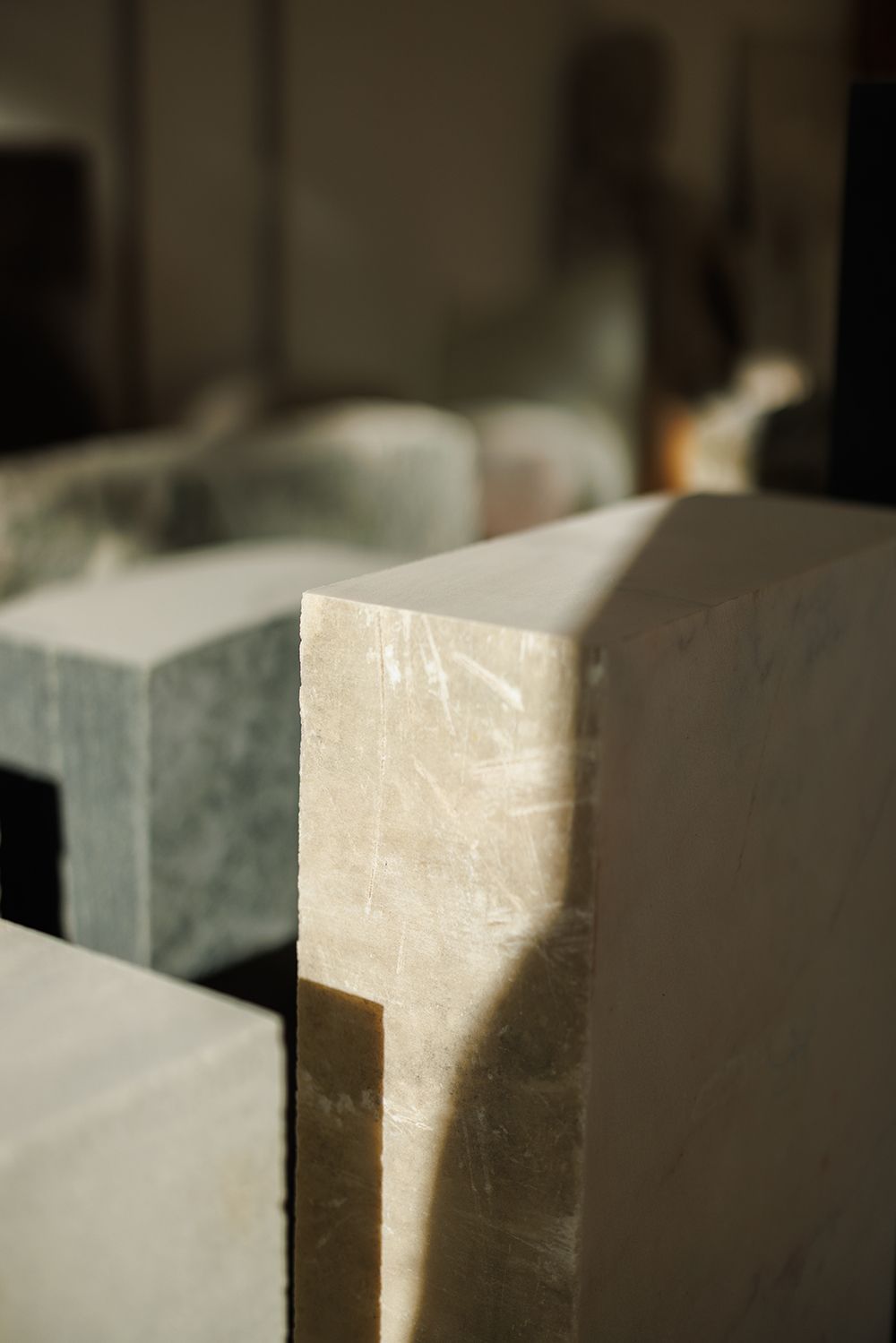 Detail of polished white marble blocks with sharp geometric edges in a stone carving studio.