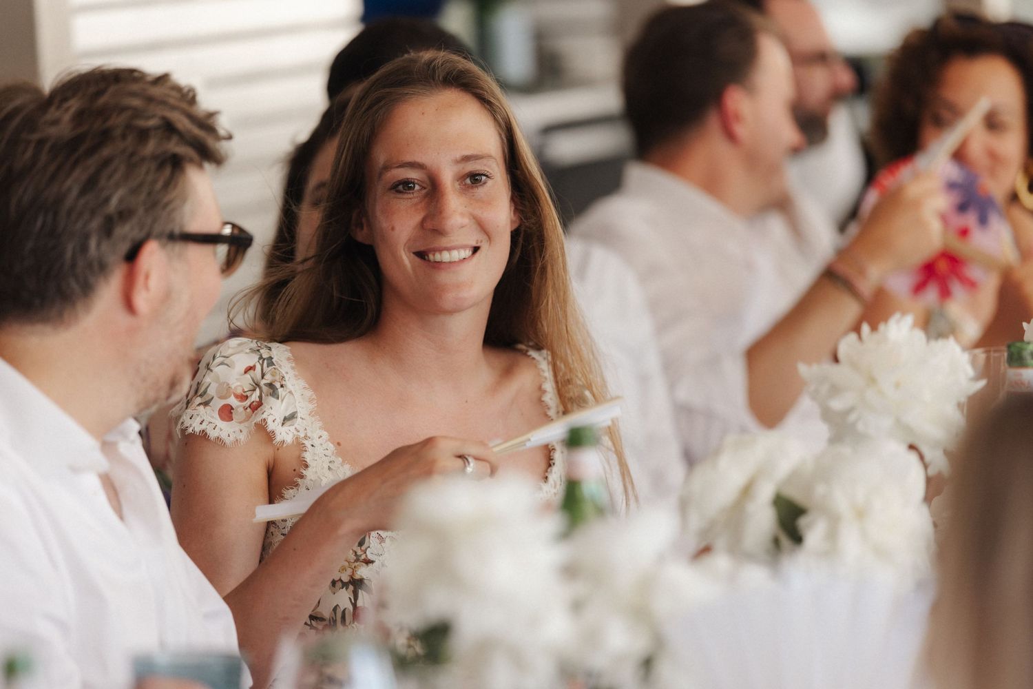 Smiling woman in floral dress chats with fellow guest at an elegant wedding reception table.
