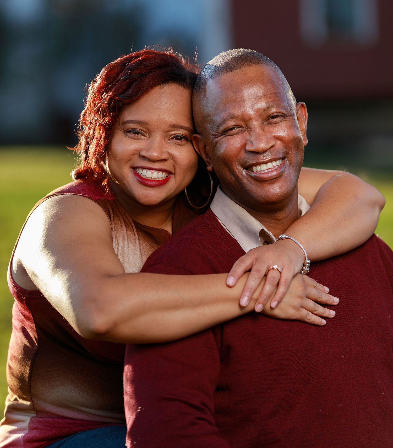 A smiling couple embraces warmly outdoors in a joyful portrait photo.