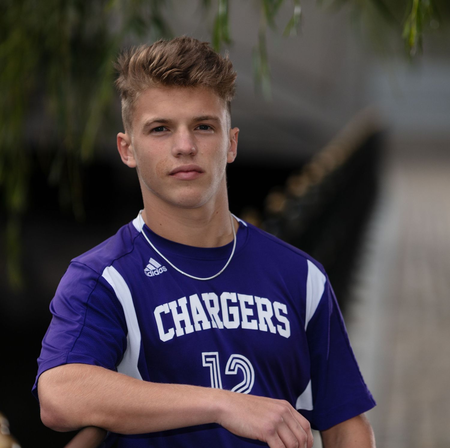 Teen athlete in purple Chargers soccer jersey number 12 posing for senior portrait photo.