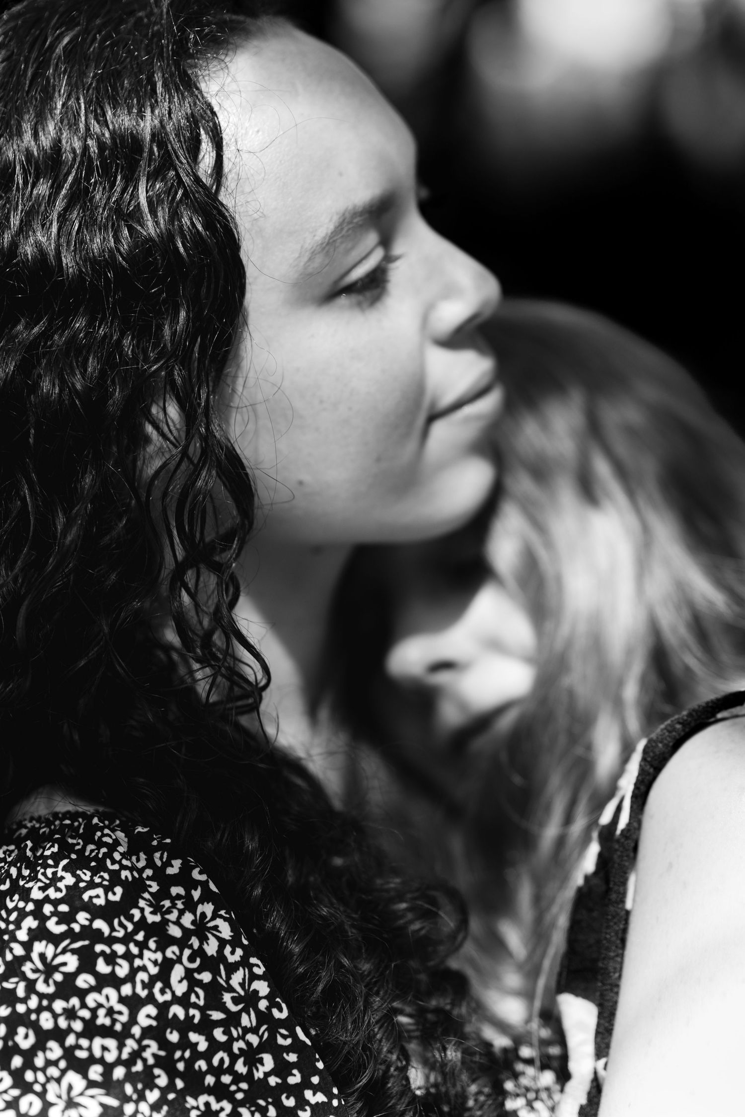 Black and white portrait of a young woman with curly hair, eyes closed, bathed in soft natural light, during LGBT couple portrait in Sussex
