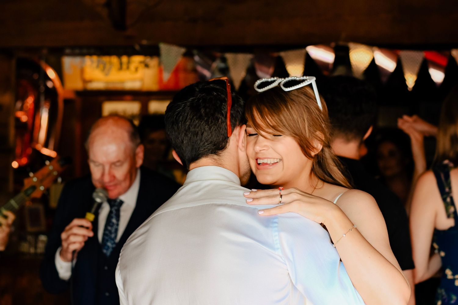 Couple sharing a joyful dance embrace at a festive indoor wedding reception with bunting decorations in Eastbourne, Sussex.
