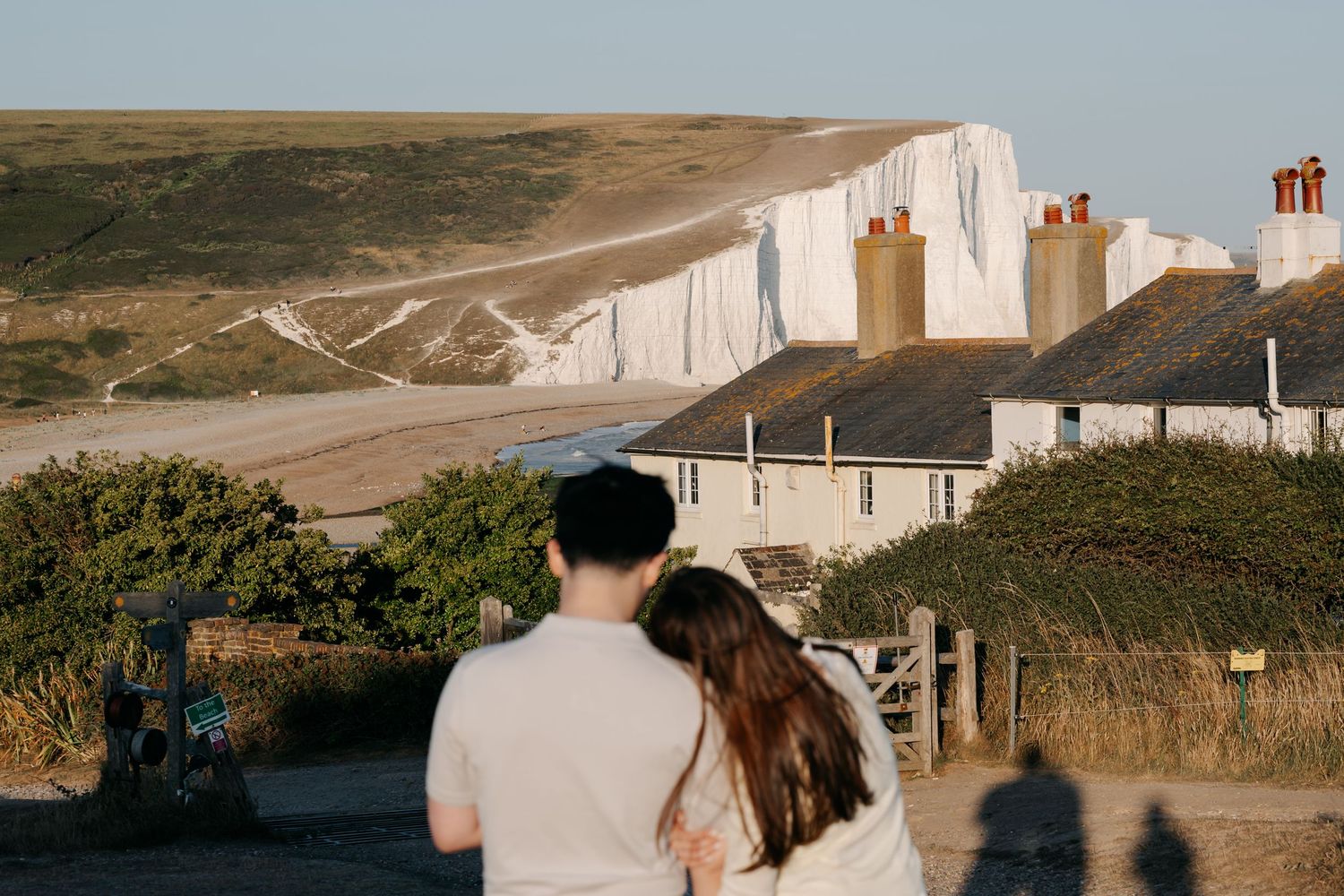 Couple embracing while admiring the iconic white chalk cliffs of Seven Sisters in East Sussex, England.
