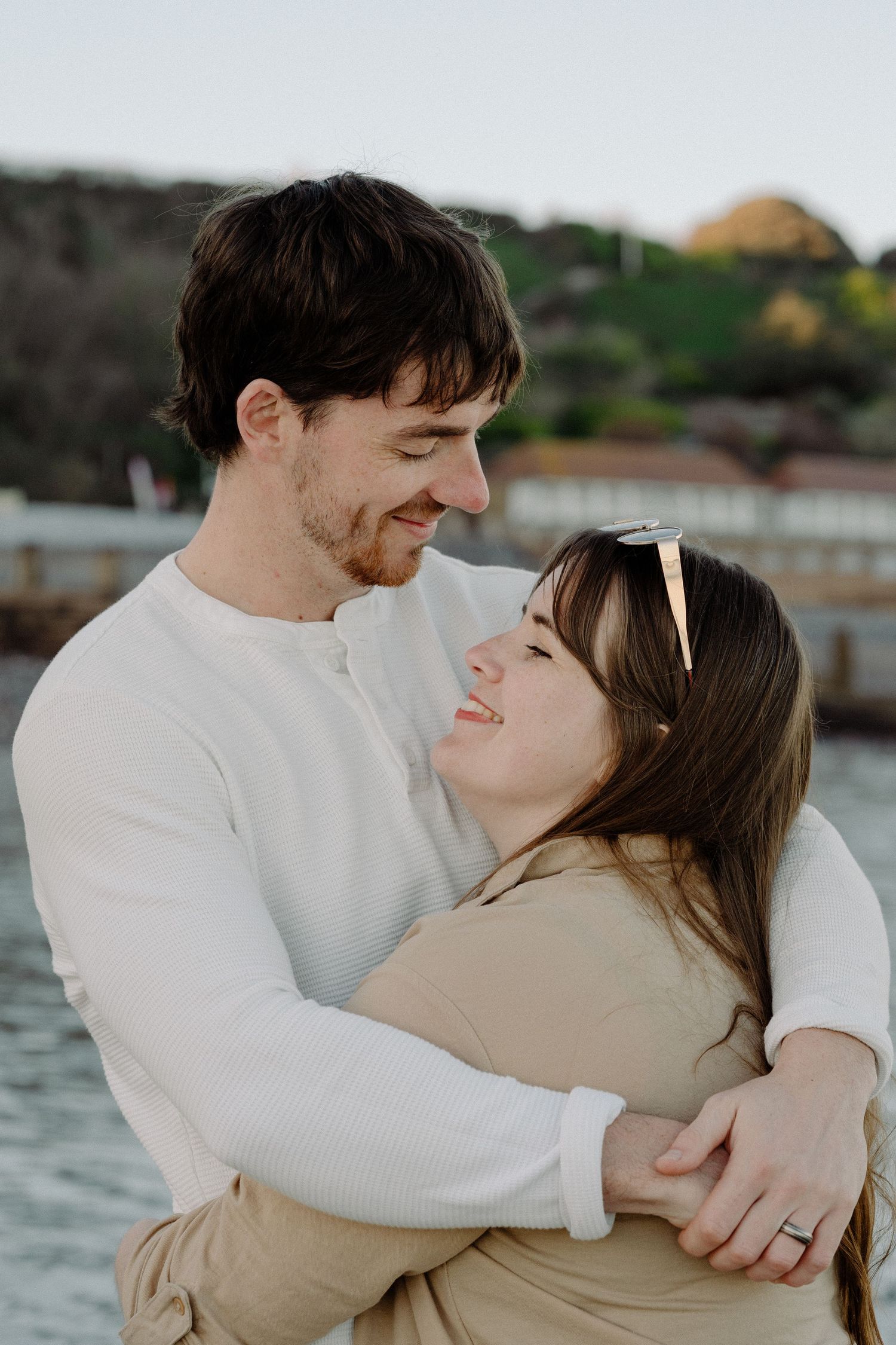 Happy couple embraces and gazes into each other's eyes during a couple portrait session on eastbourne beach at golden hour