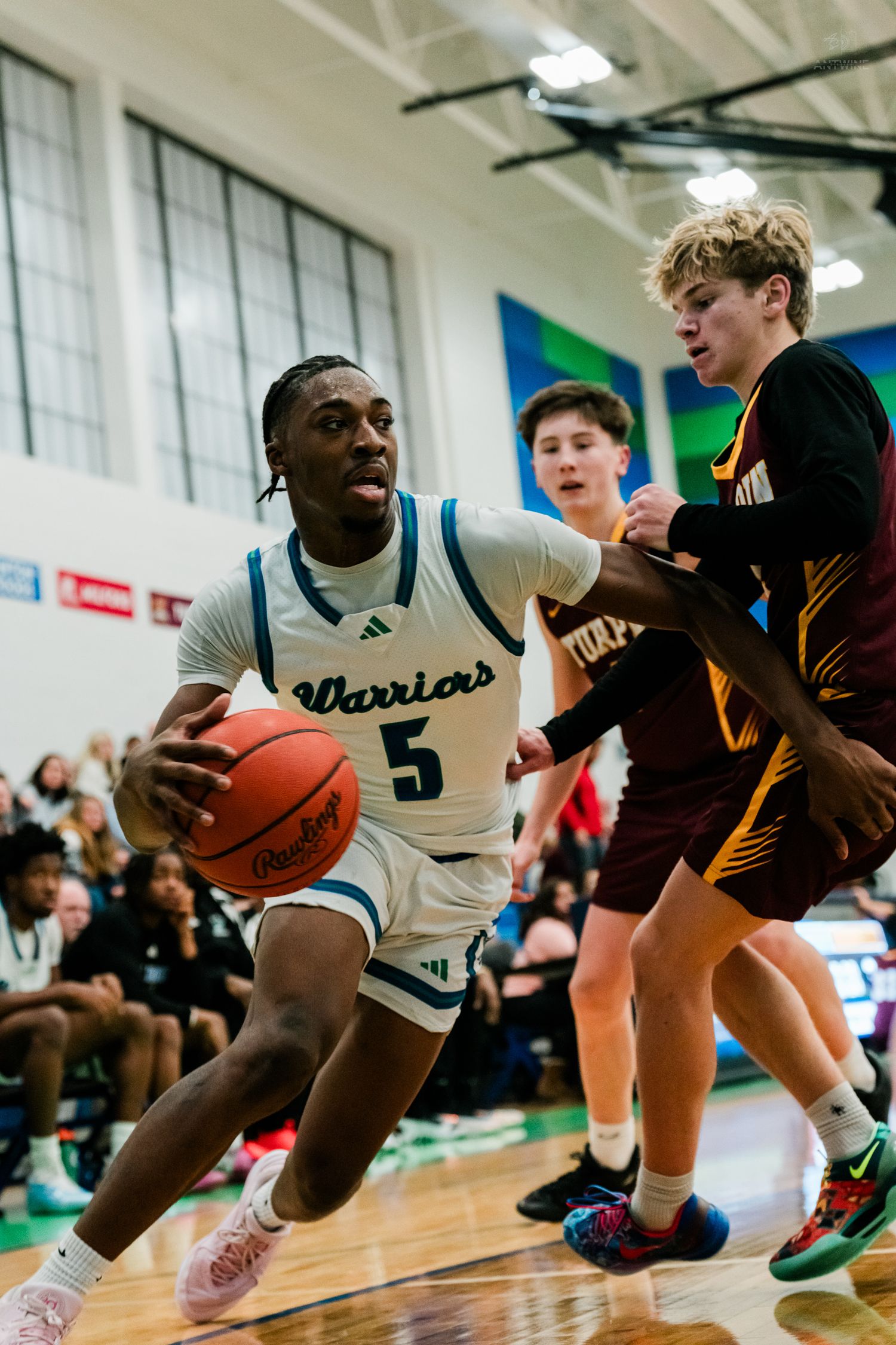 Winton Woods Warriors player #5 drives to the basket against Turpin defenders during a high school basketball game.