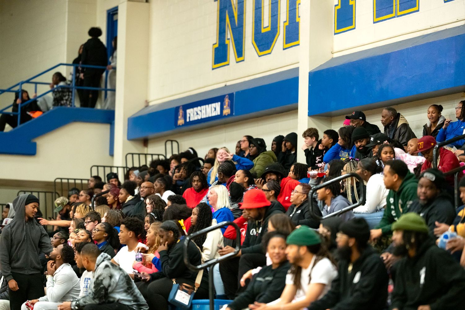 Large crowd of fans fills bleachers at high school basketball game.