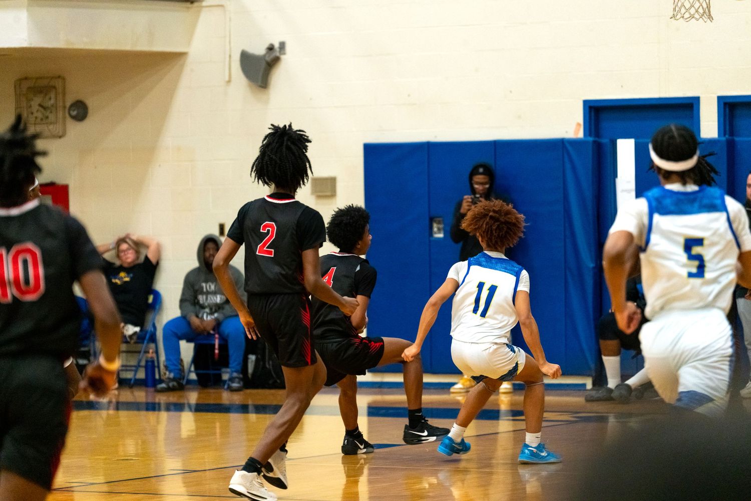 High school basketball players compete on the court with number 2 defending number 11.