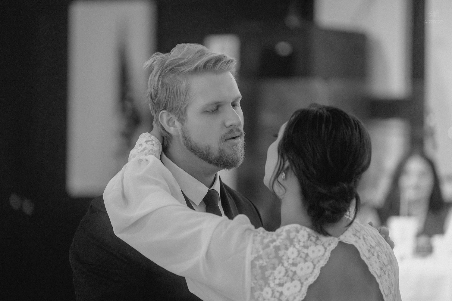 Black and white photo of a groom tenderly touching his brides face during their first dance.