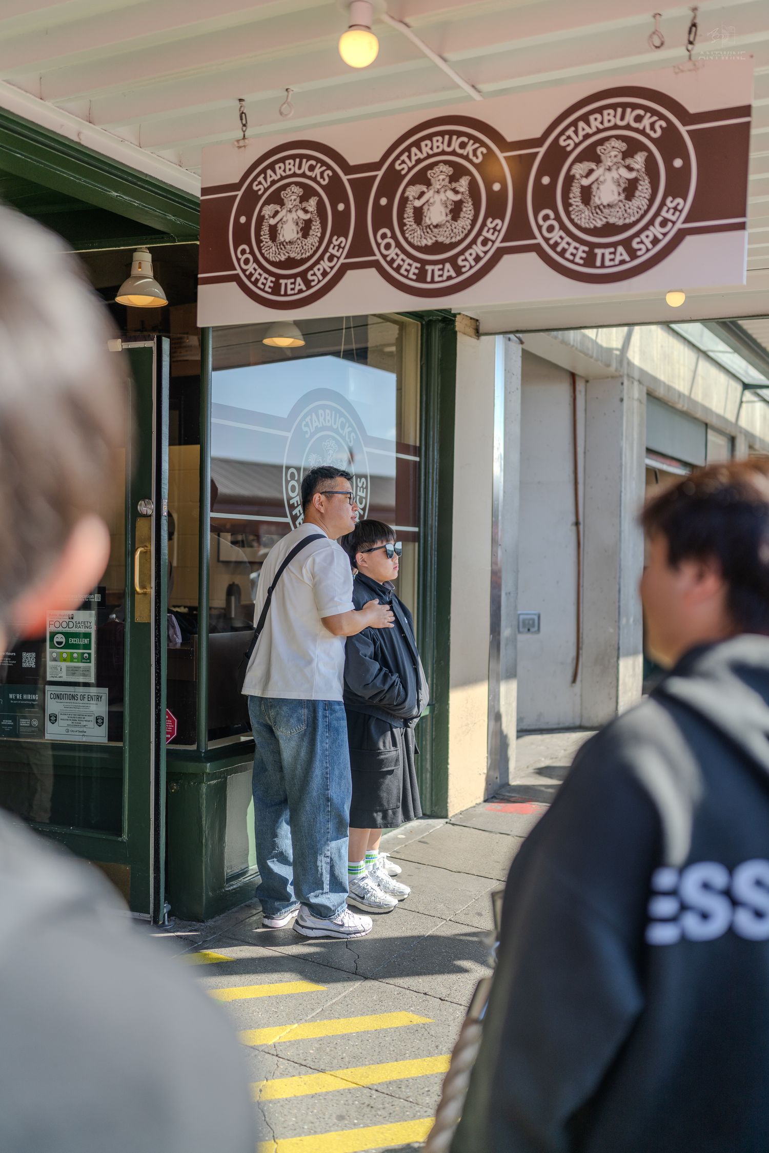 Customers waiting outside the original Starbucks Coffee Tea Spices store entrance at Pike Place Market Seattle.