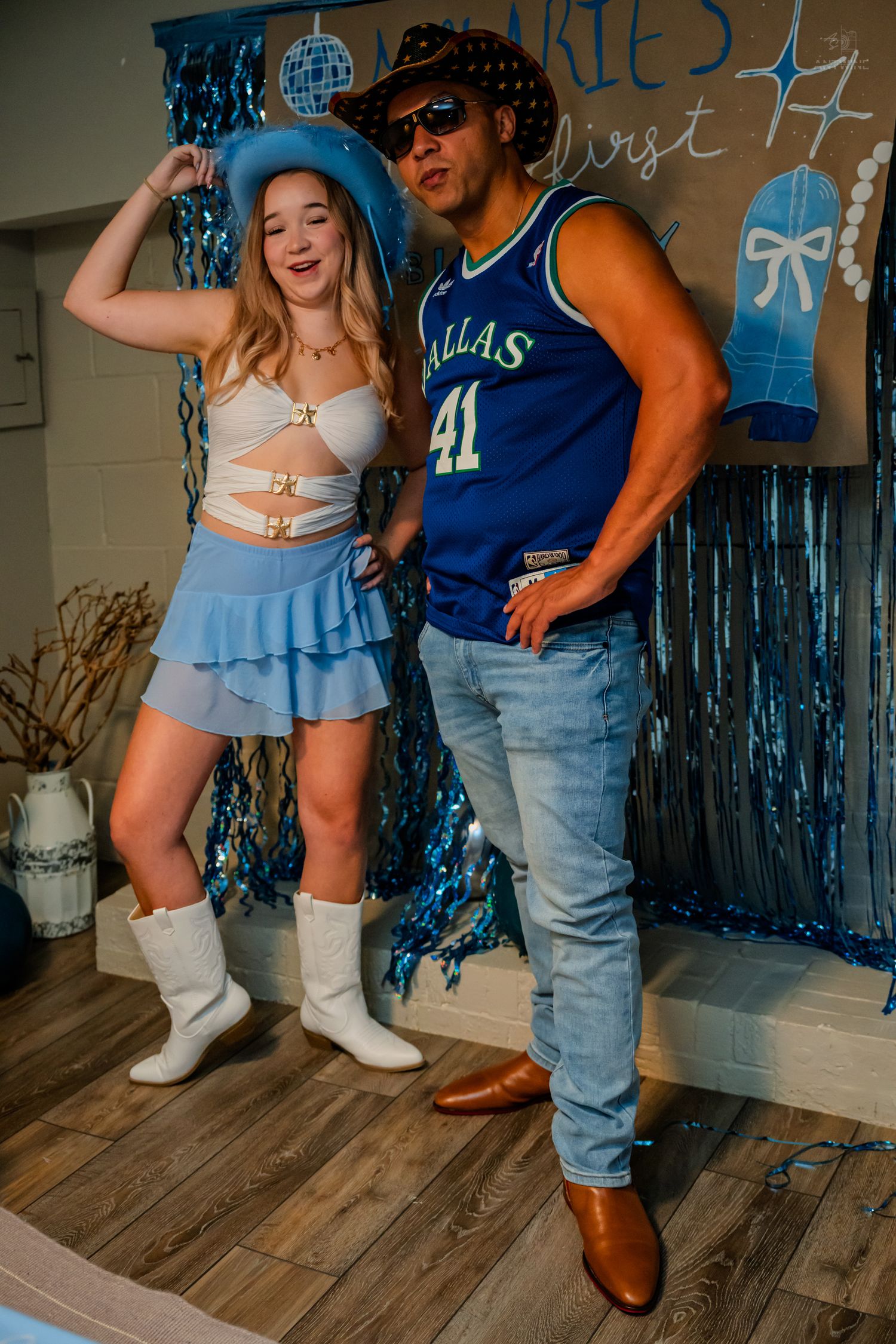 Couple dancing and laughing in blue Western outfits at a festive birthday party celebration.