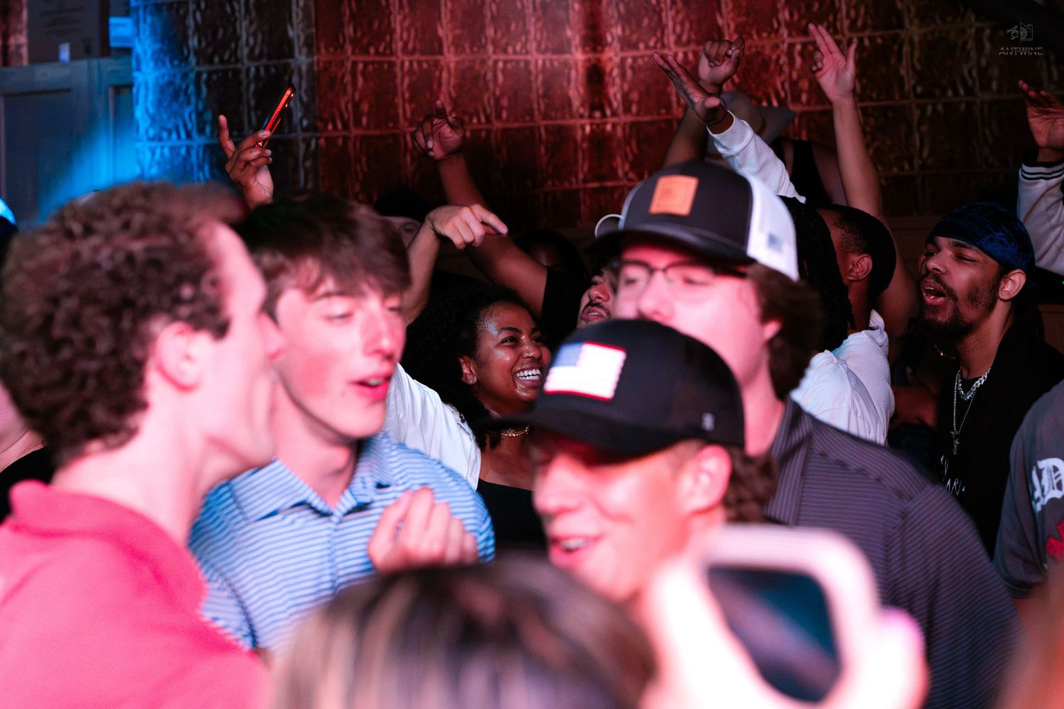 Energetic group of young people celebrating and cheering at a packed nightclub party.