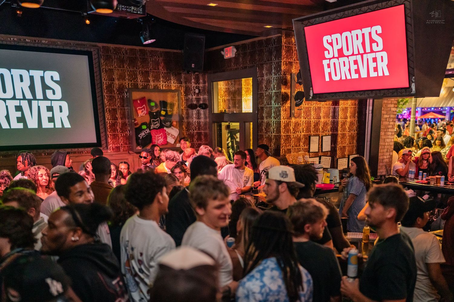 Packed sports bar crowd watching Sports Forever on large screens during a lively event.