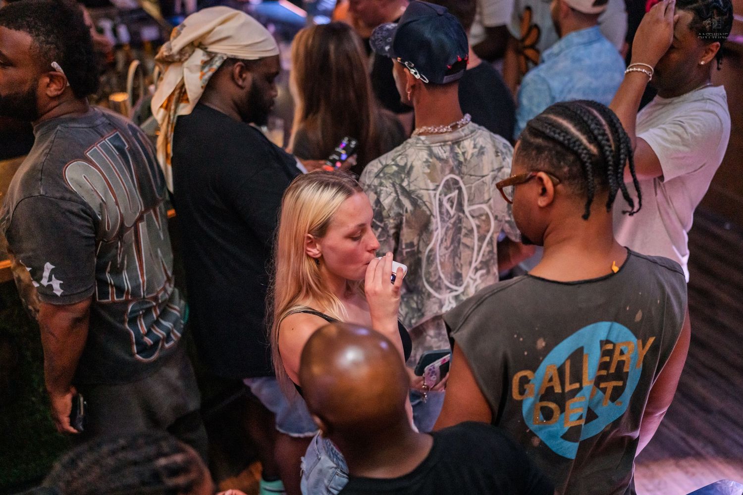 Young woman smiling while mingling with friends at a busy nightclub.