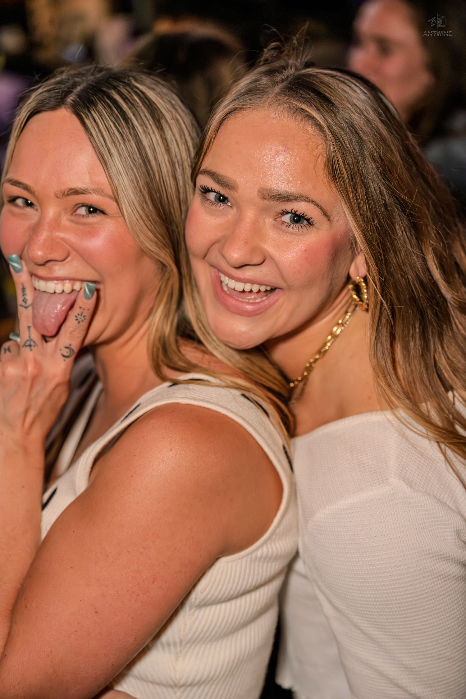 Two blonde women pose together playfully at a fun nightclub party event.