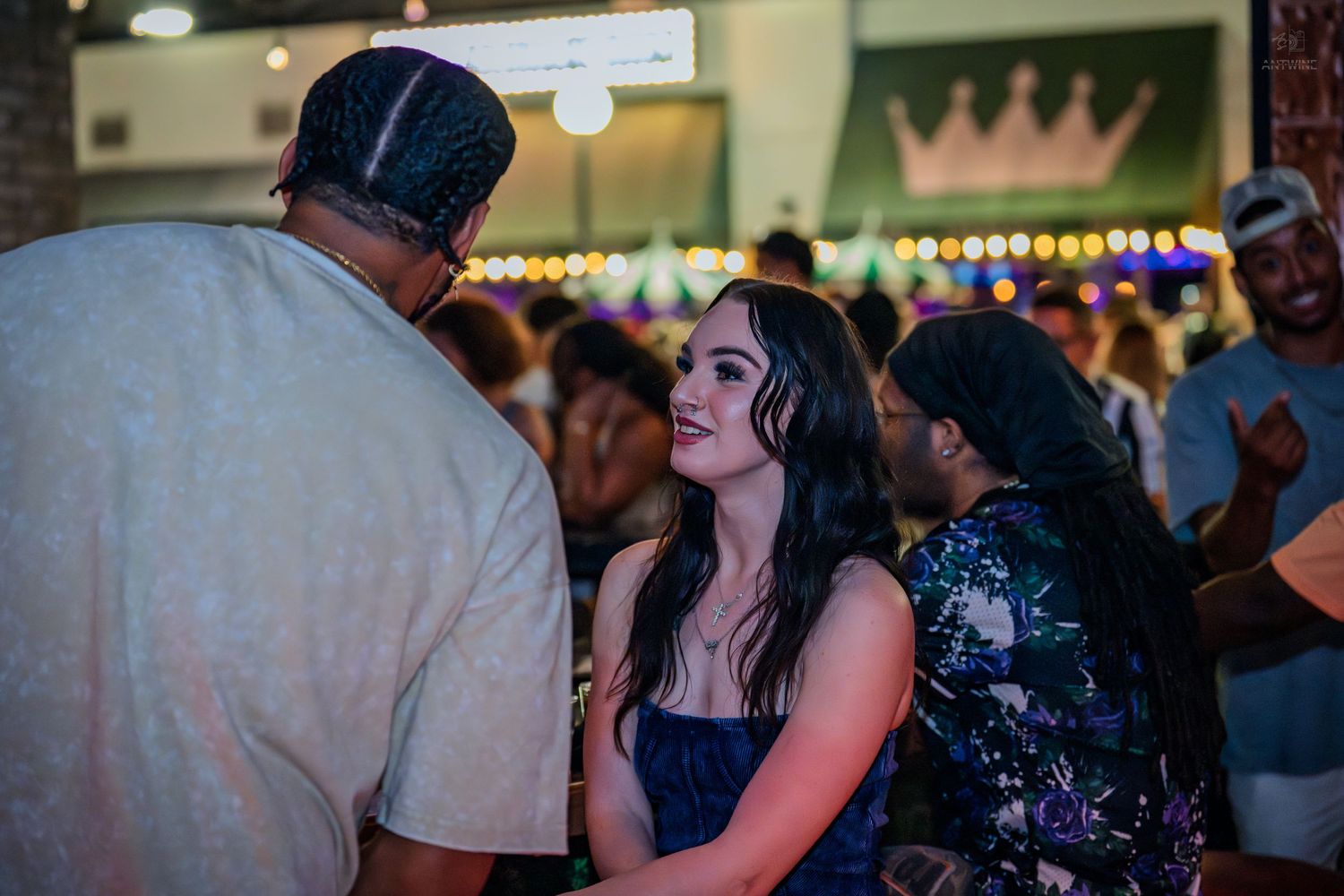 Young woman smiling and socializing at an indoor party venue with string lights.