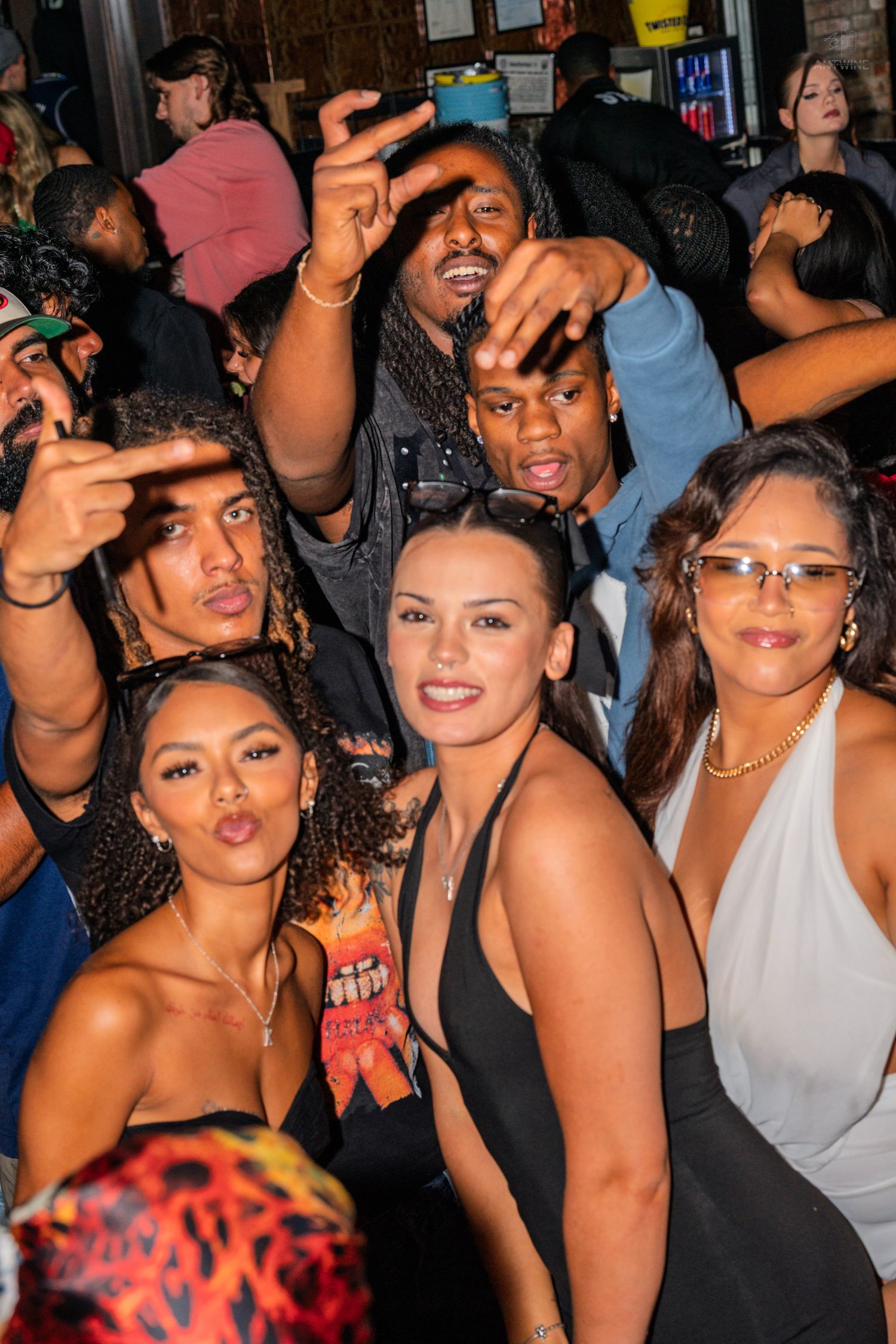 Group of friends posing and smiling together at a crowded indoor party event.