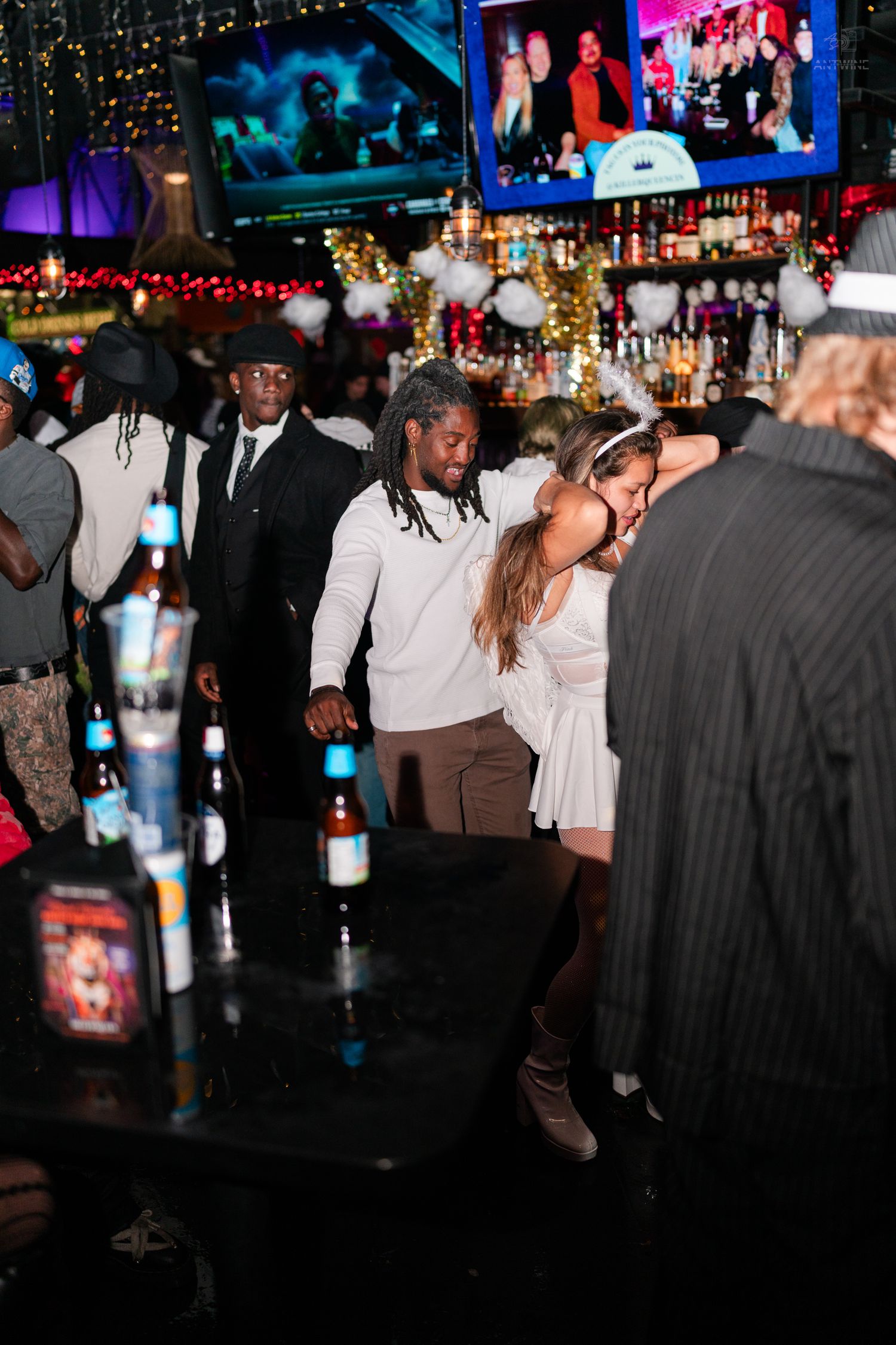 Couple dancing together at a festive nightclub party with holiday decorations.