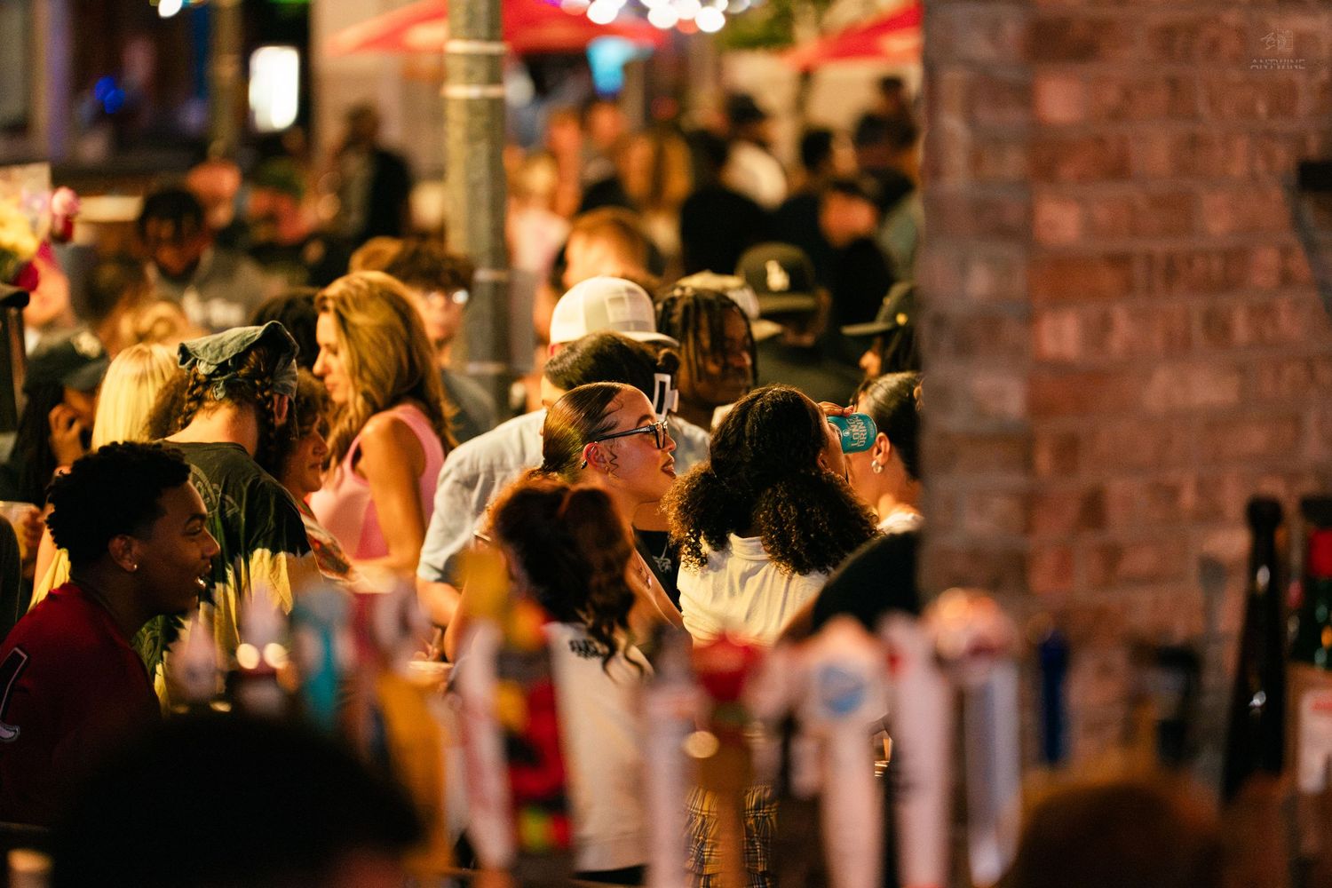 Large crowd of people socializing at an outdoor nighttime bar or festival event.