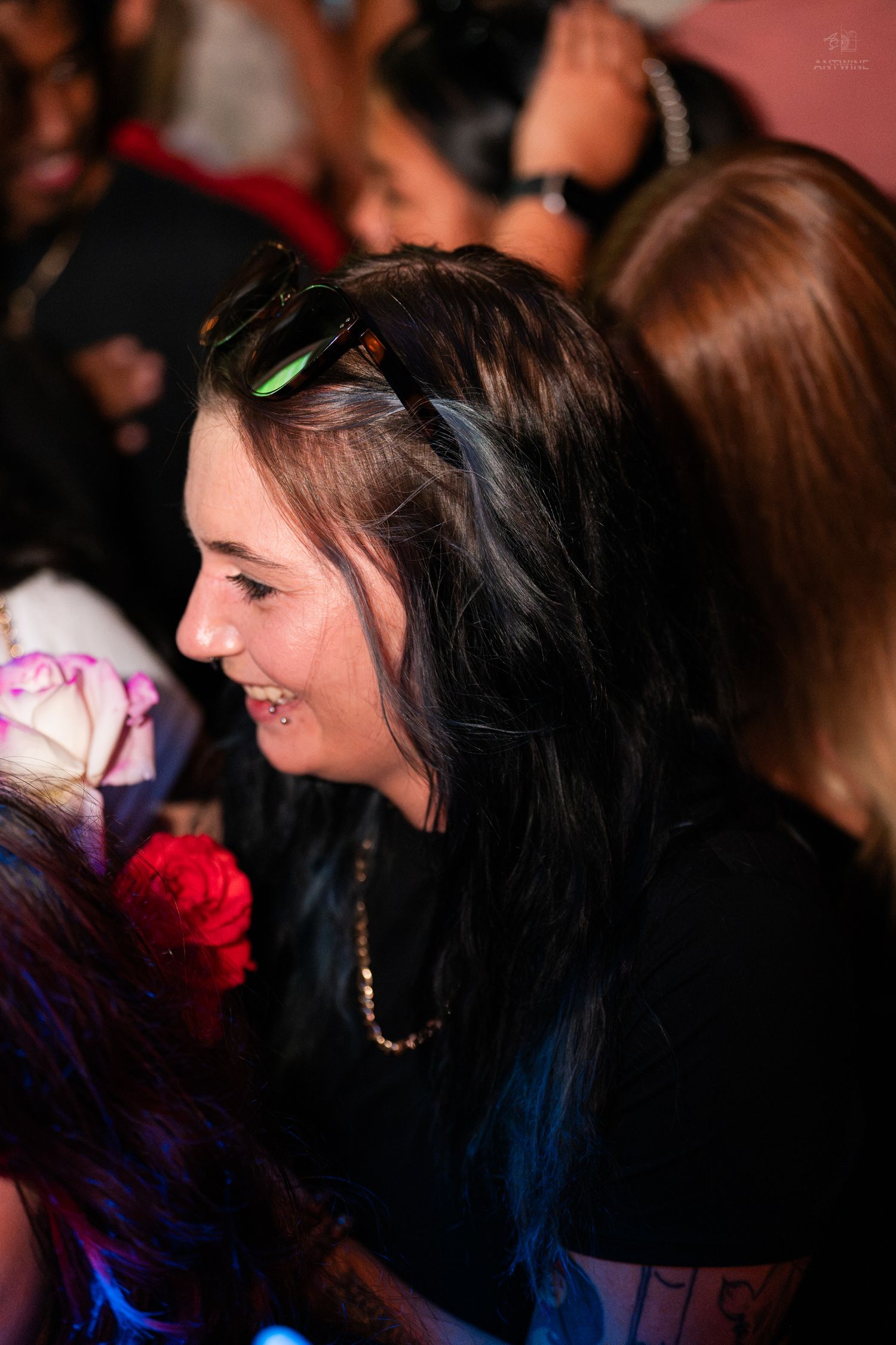 Young woman with dark hair and sunglasses smiling at a nightclub event.