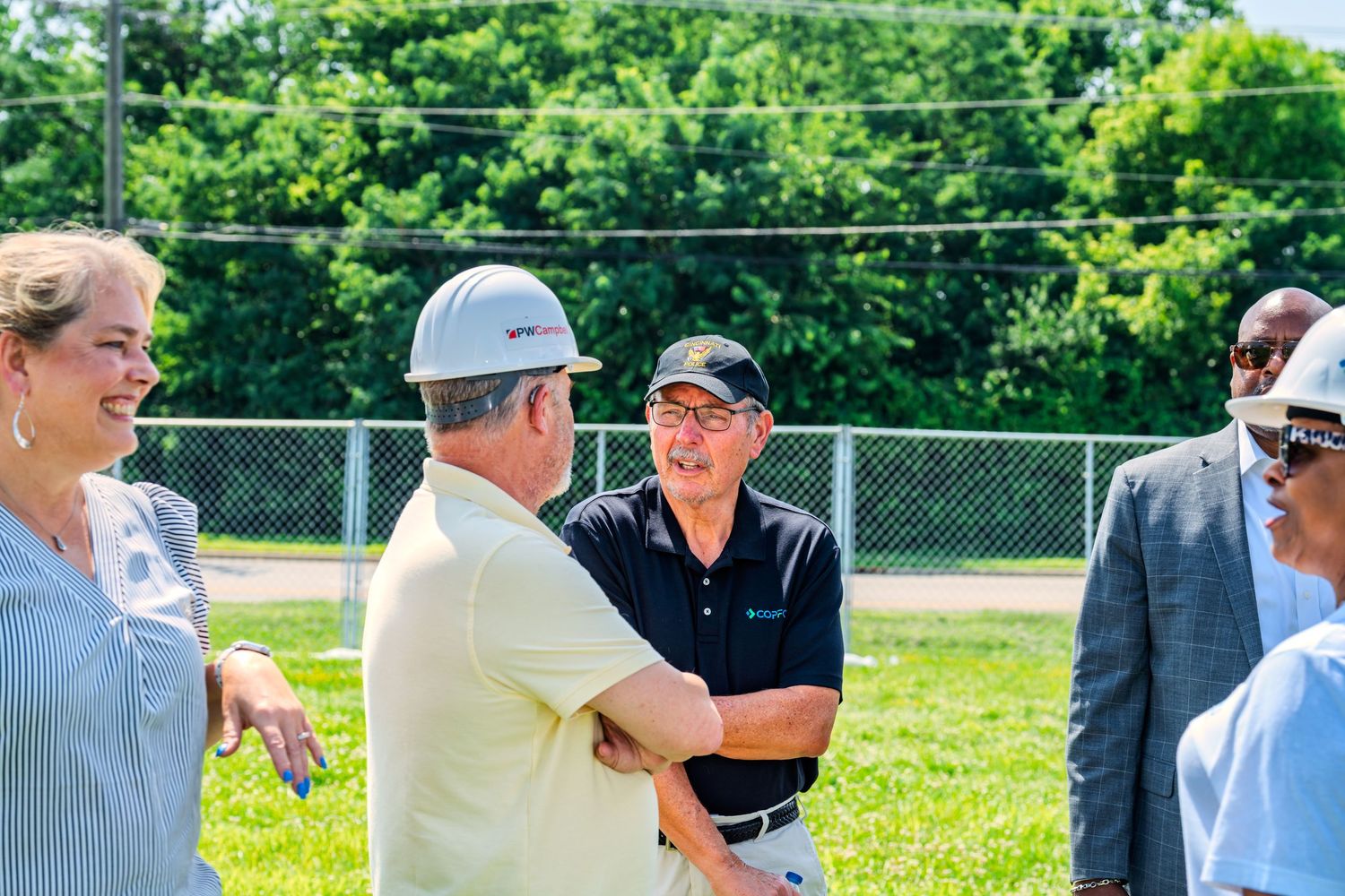 Group of people networking and shaking hands at an outdoor construction groundbreaking ceremony.