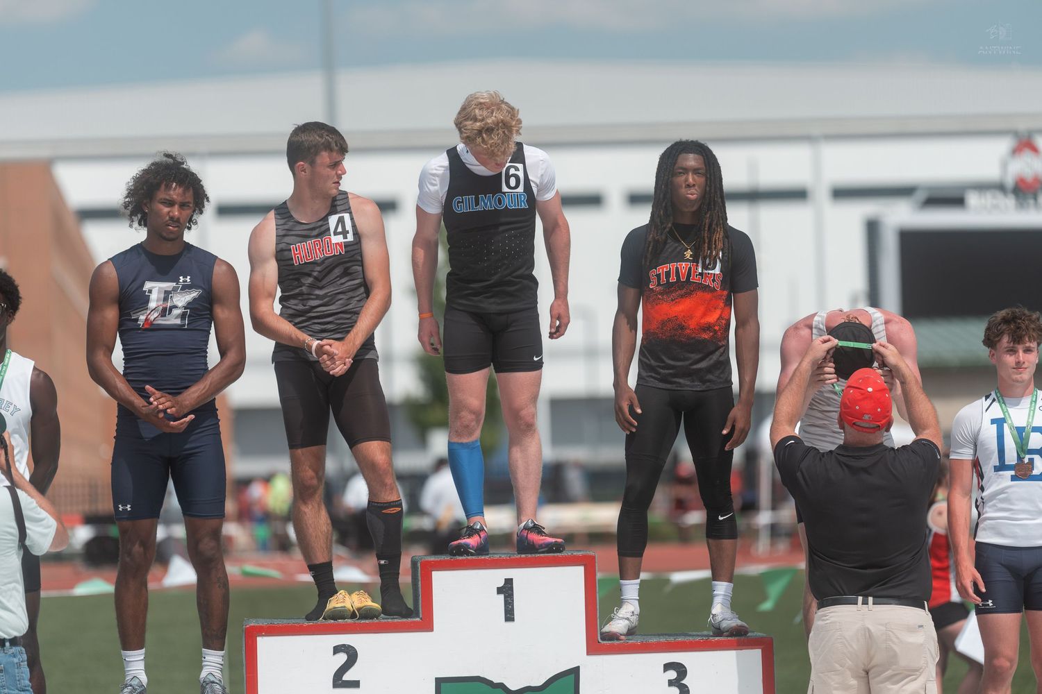 Male high school athletes pose on numbered award podium at OHSAA track and field championship.