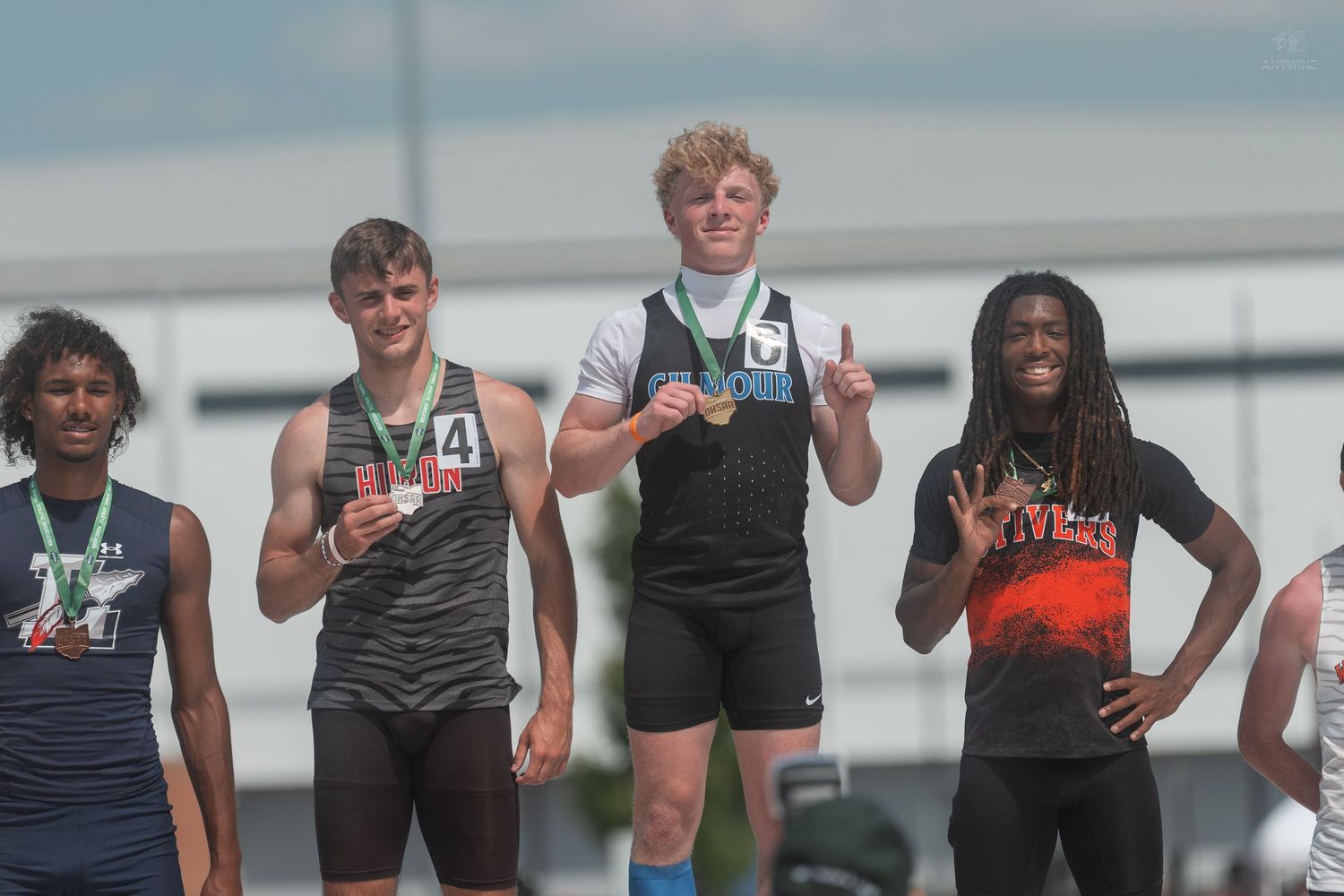 High school boys celebrate track medals on podium at OHSAA Division IV 200 meter dash championship.