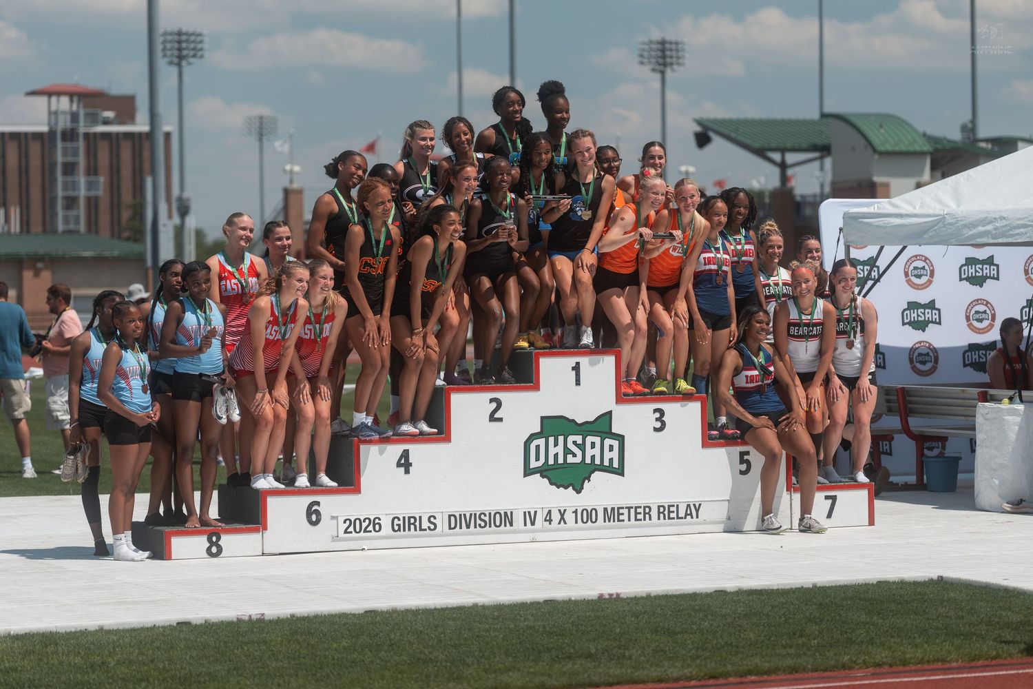 Girls relay teams grouped together on OHSAA Girls Division IV 4x100 Meter Relay championship podium.