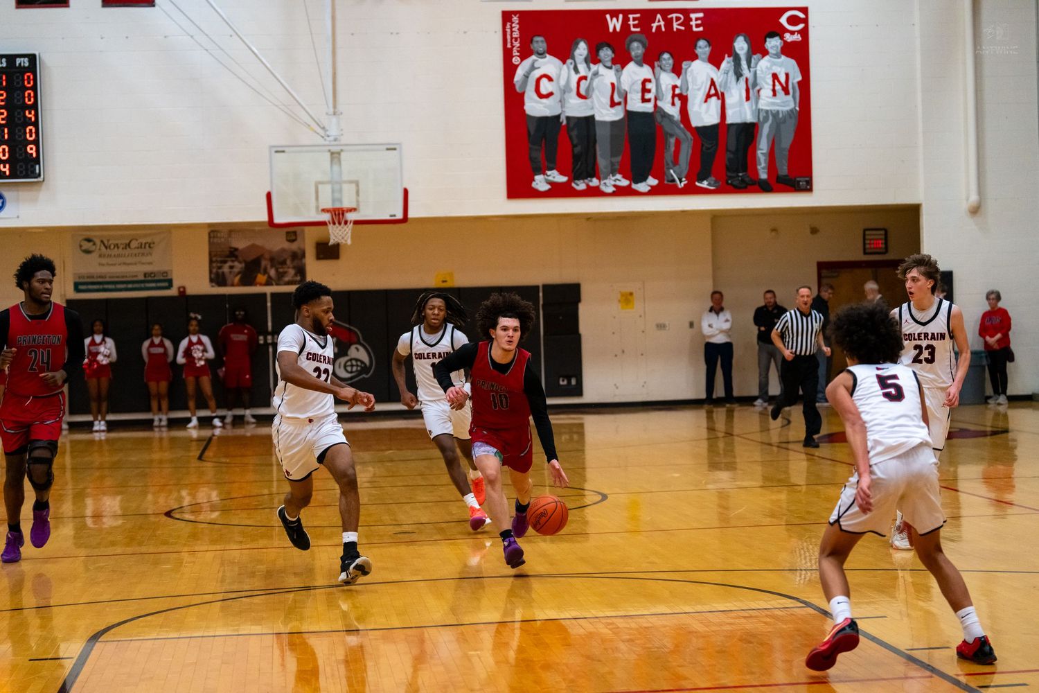 High school basketball players in red and white uniforms compete during fast break at Coleman gymnasium.