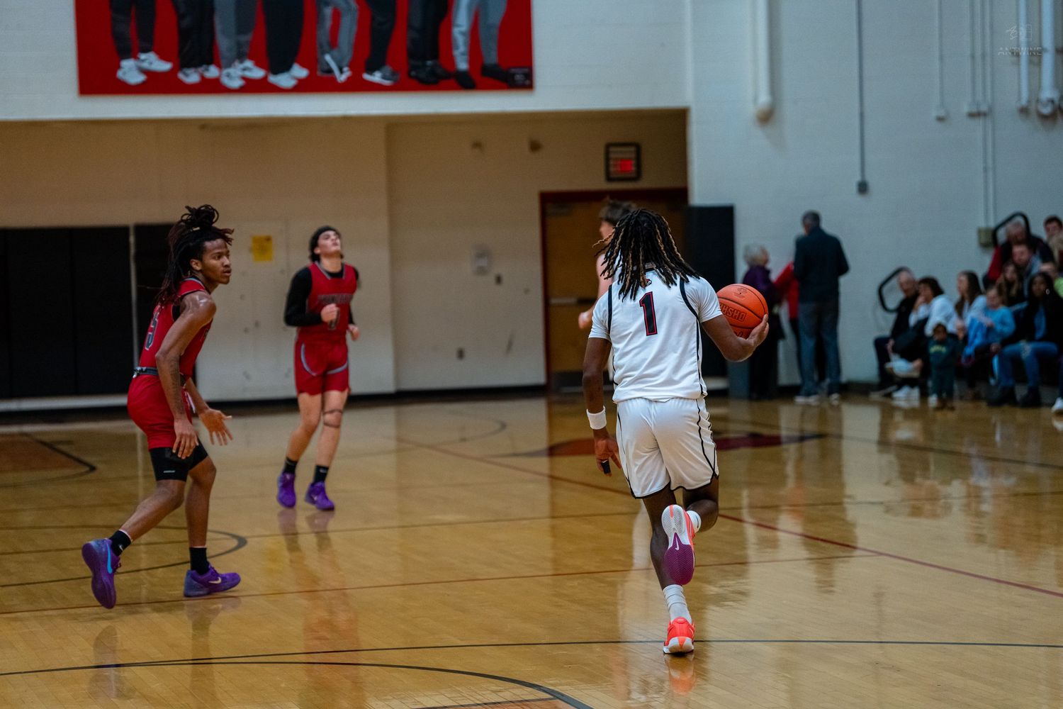 Female basketball player dribbles downcourt during a high school girls basketball game in a gymnasium.