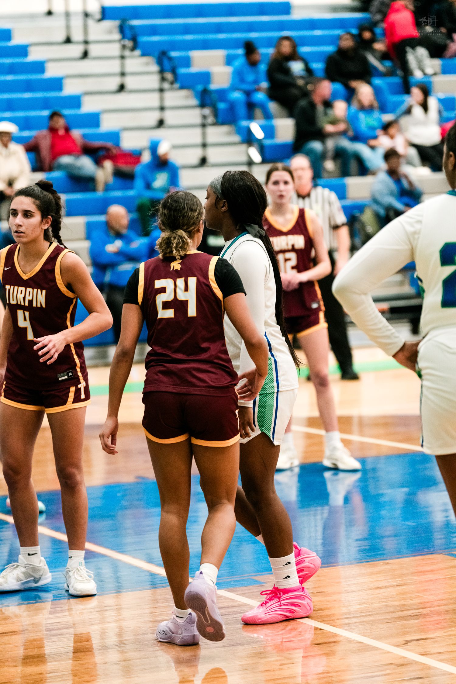 Warriors and Turpin number 24 players interact near the free throw line during a girls basketball game.