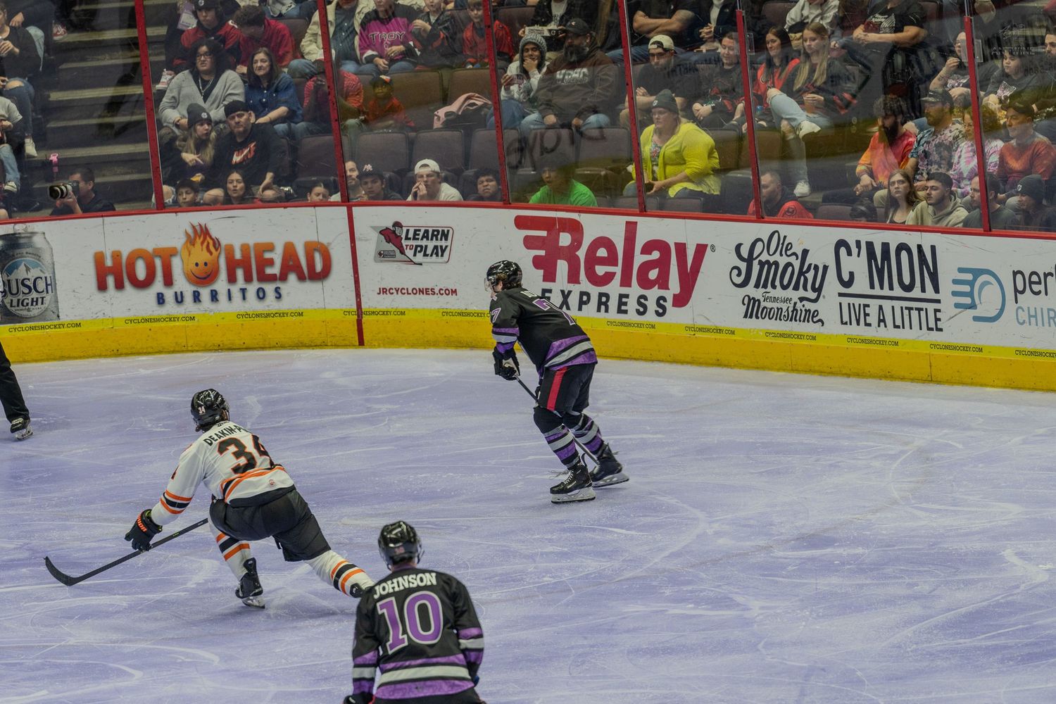 Hockey players skate toward the puck during a competitive minor league ice hockey game.