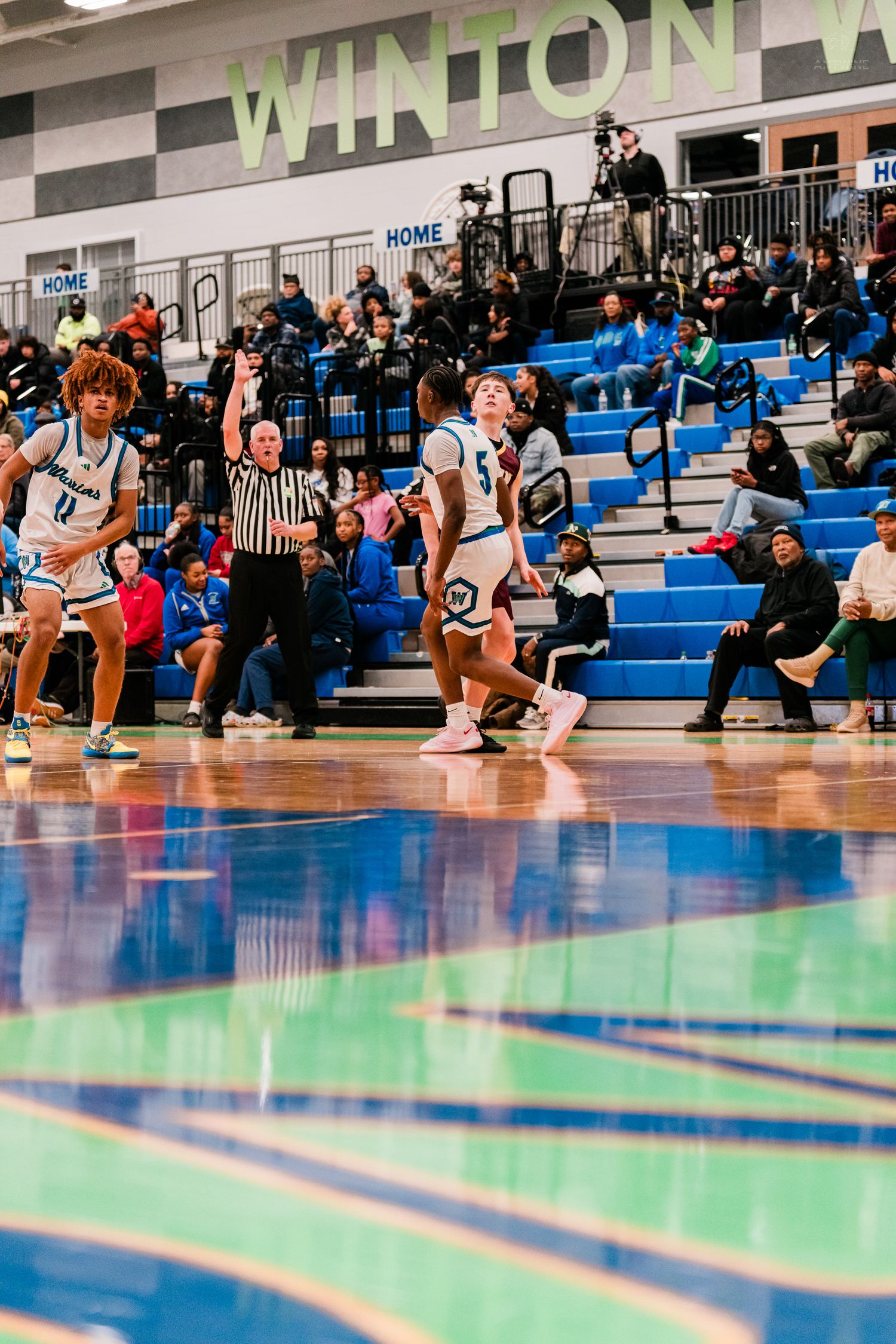 Winton Woods Warriors basketball players react after a play during a home game with fans in the stands.