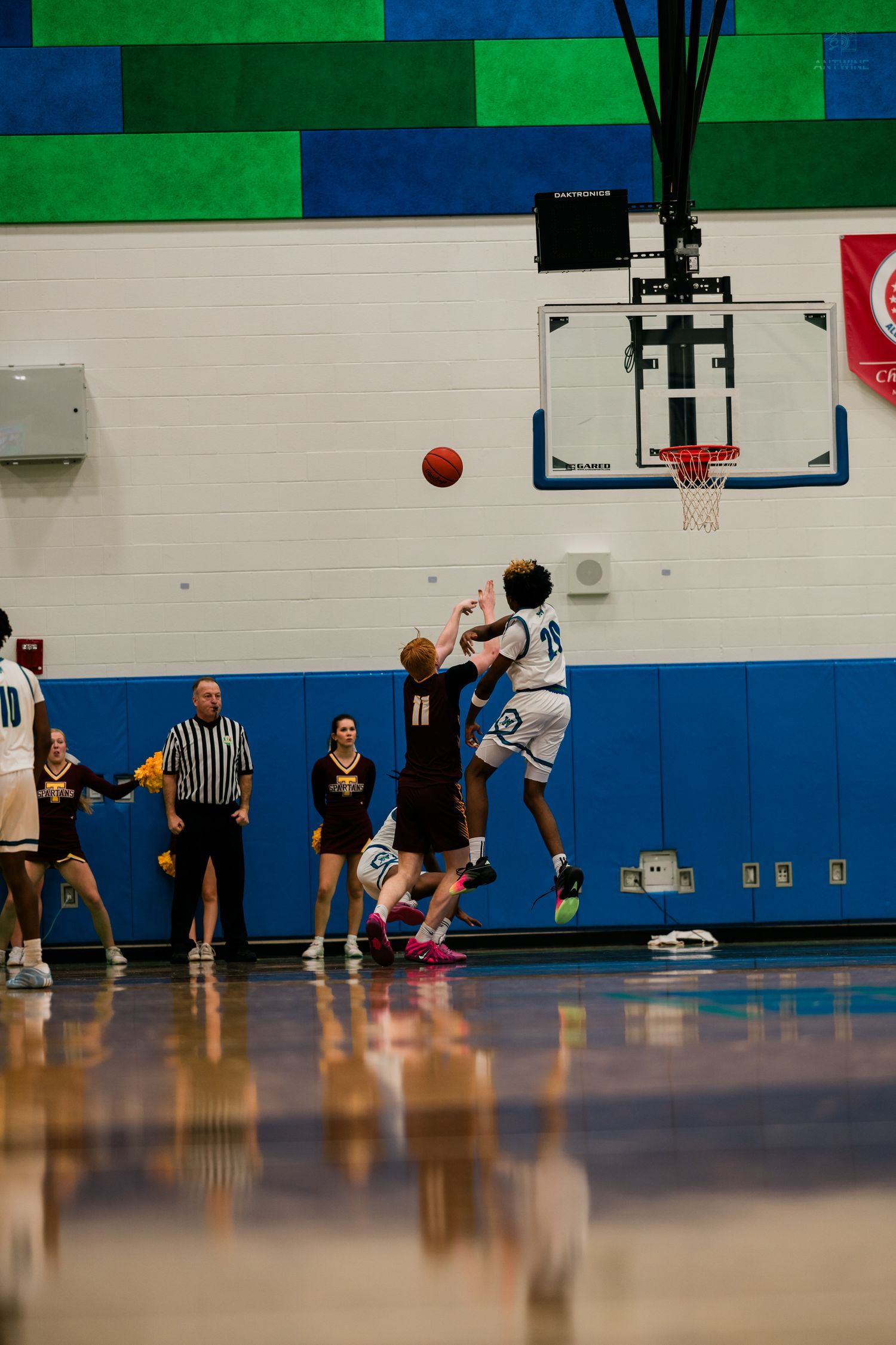 Two basketball players contest a shot near the hoop during a high school game between Warriors and opposing team.