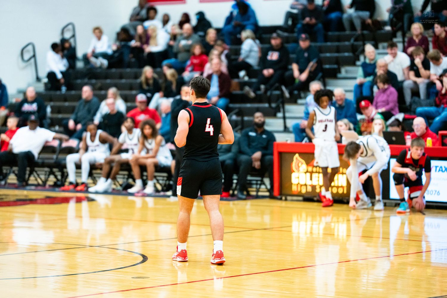 A red-uniformed basketball player reacts emotionally as an opponent in number 23 walks past during a game.