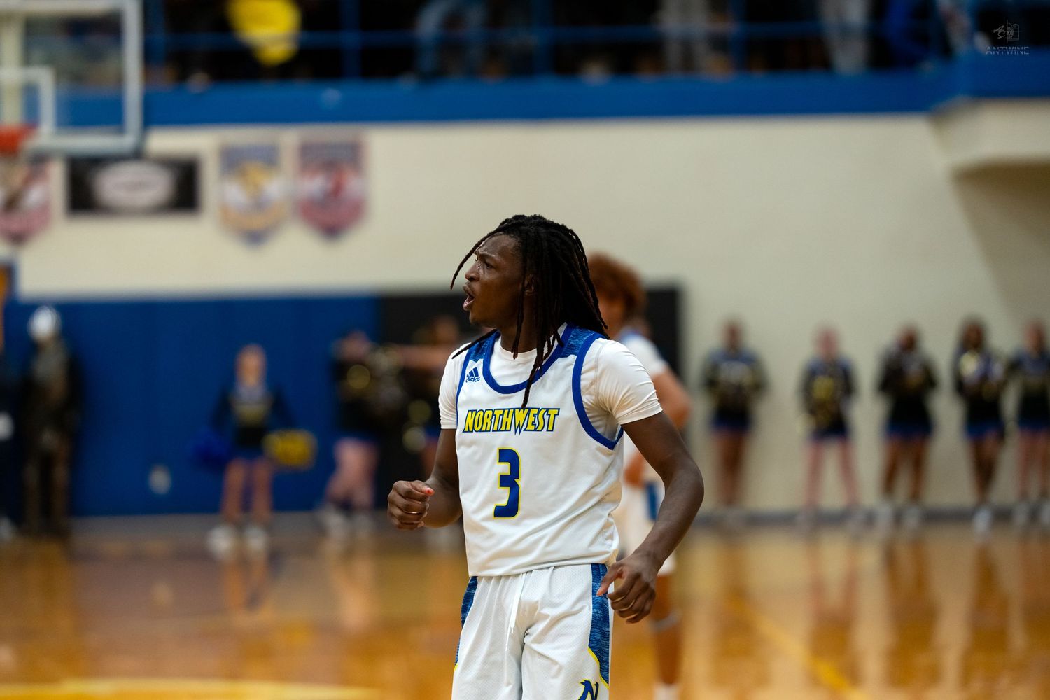 High school basketball player wearing number 3 blue and gold uniform stands on gymnasium court.