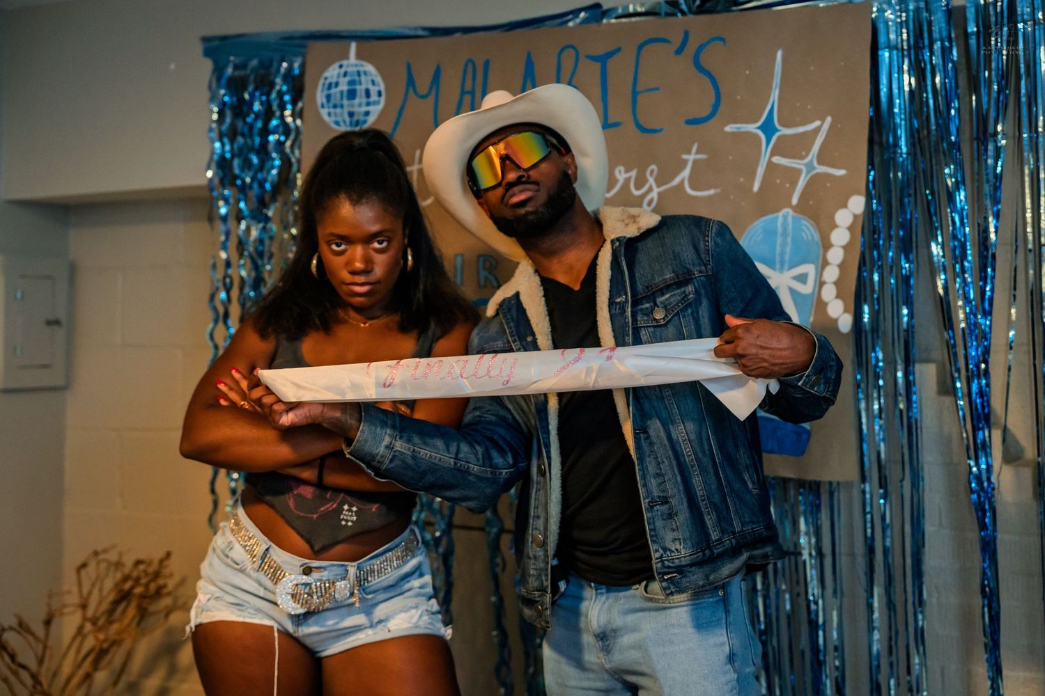 Two people examine a banner at Malarie's birthday party with blue decorations.