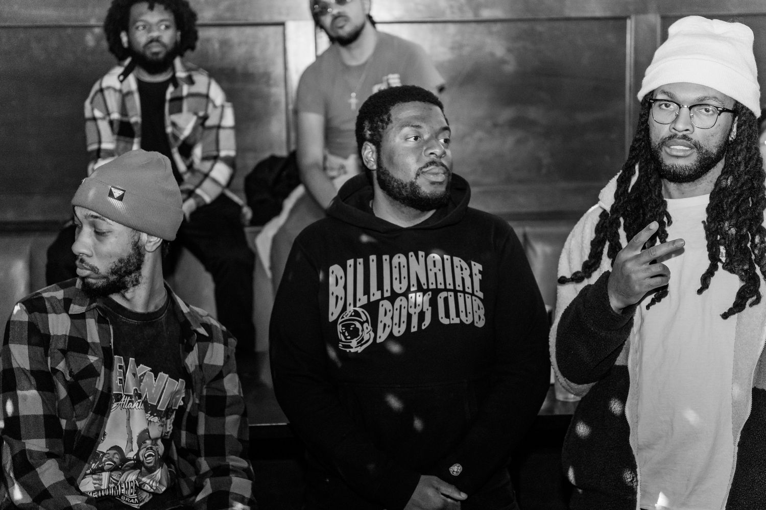 Black and white photo of a group of men posing together, one wearing a Billionaire Boys Club sweatshirt.
