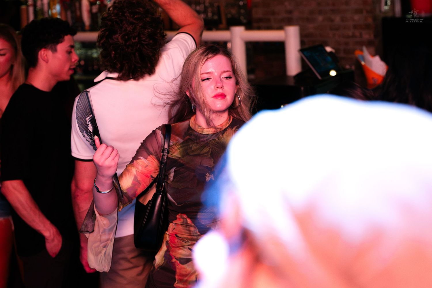 Woman in camouflage top dancing energetically in a lively nightclub crowd.